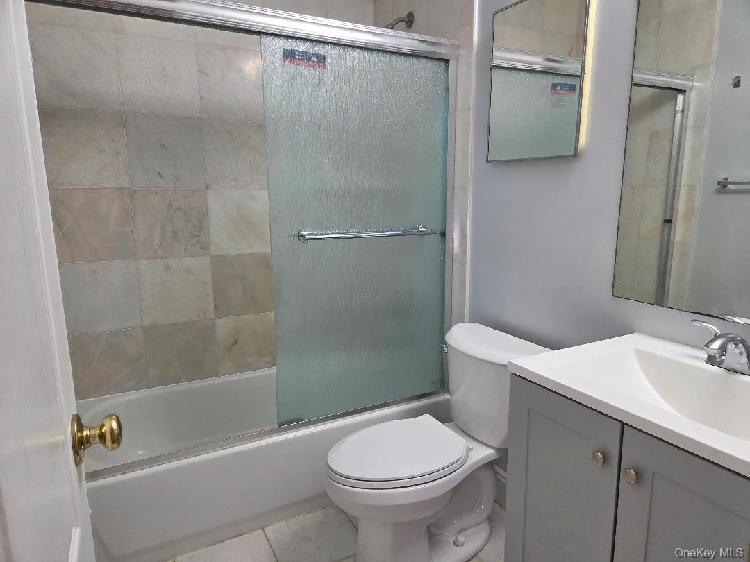 Bathroom featuring toilet, tile patterned floors, combined bath / shower with glass door, and vanity Bathroom featuring toilet, tile patterned floors, combined bath / shower with glass door, and vanity