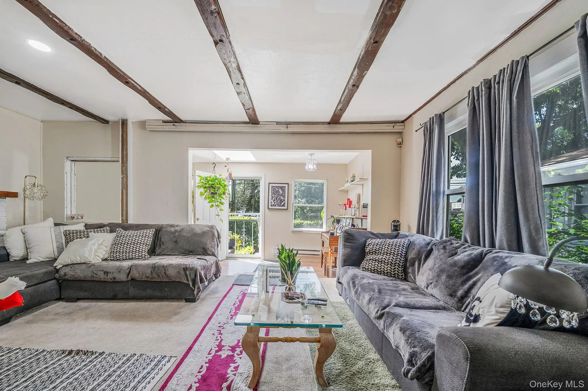 Carpeted living room featuring beam ceiling and plenty of natural light Carpeted living room featuring beam ceiling and plenty of natural light