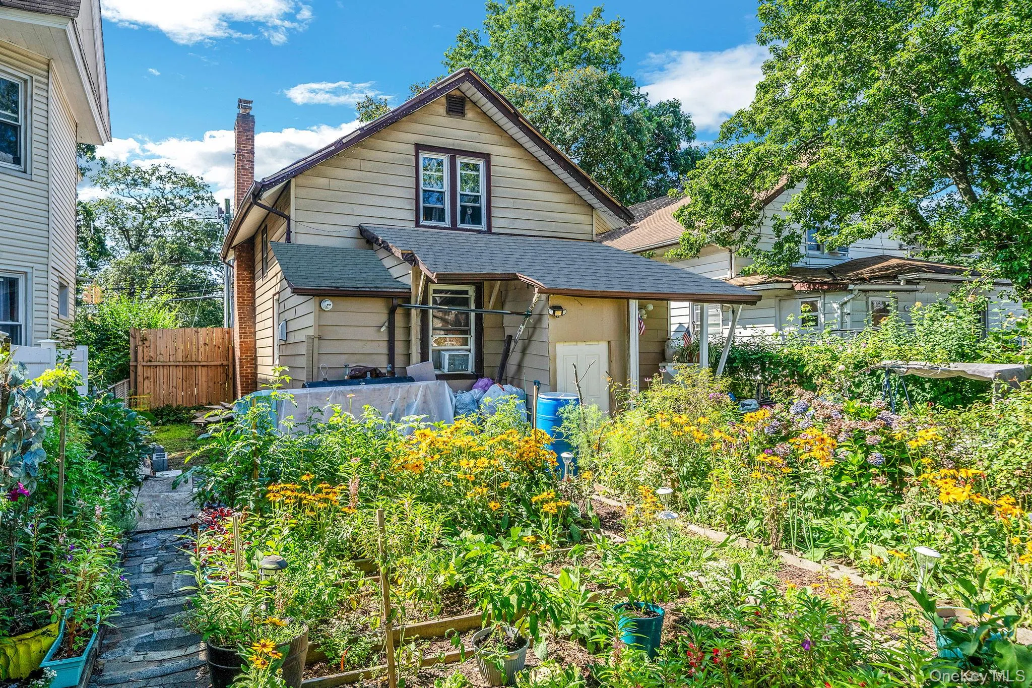View of front facade featuring roof with shingles, a garden, and a chimney View of front facade featuring roof with shingles, a garden, and a chimney