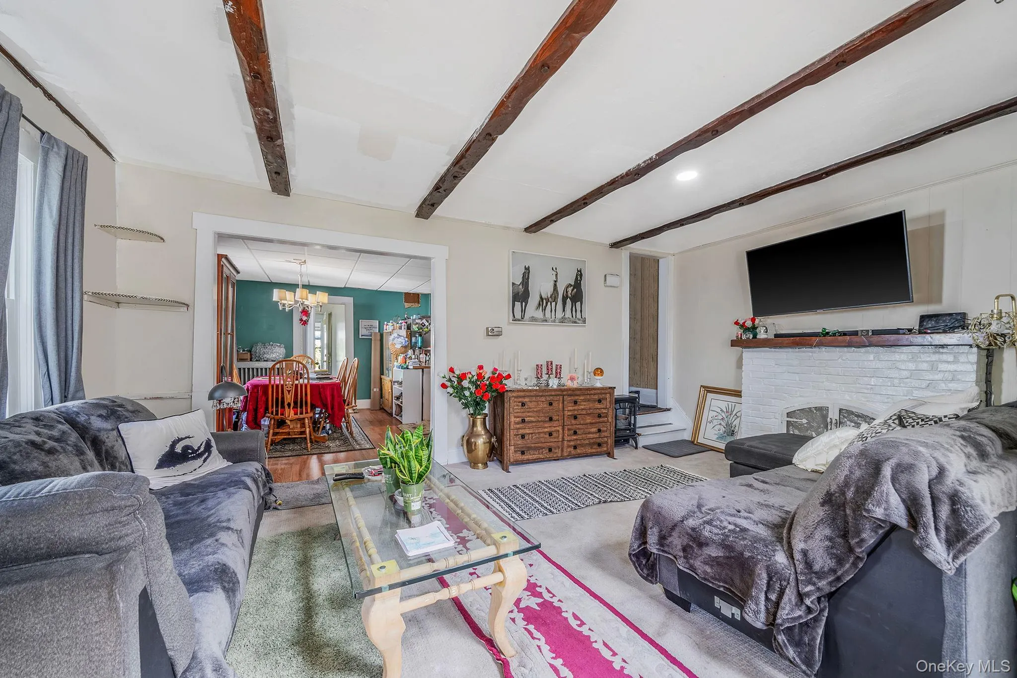 Living area featuring a chandelier, beam ceiling, and wood finished floors Living area featuring a chandelier, beam ceiling, and wood finished floors