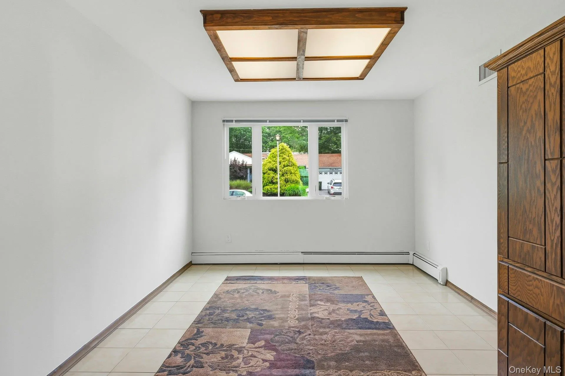 Bright room with a three-panel window, white walls, and light-toned tile flooring Bright room with a three-panel window, white walls, and light-toned tile flooring