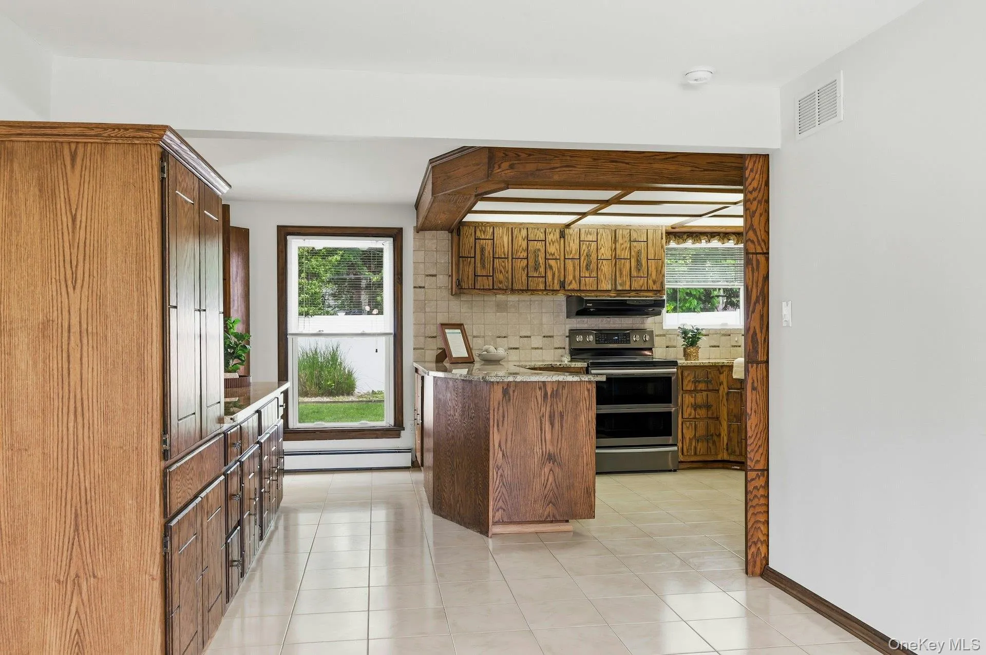 Expansive kitchen featuring wood cabinetry, a central island, and a tile backsplash Expansive kitchen featuring wood cabinetry, a central island, and a tile backsplash