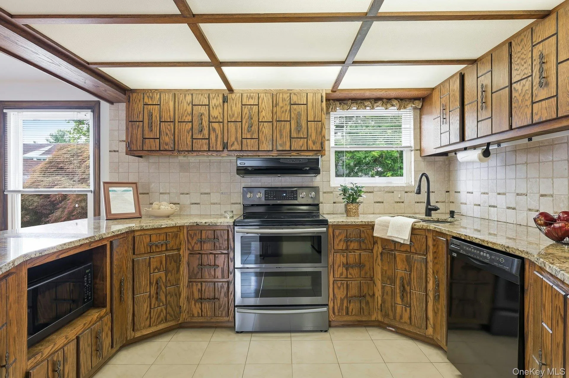 Kitchen featuring wood cabinetry, light-toned tiled backsplash, granite-finish countertops, and a full suite of appliances including a double oven range and built-in microwave Kitchen featuring wood cabinetry, light-toned tiled backsplash, granite-finish countertops, and a full suite of appliances including a double oven range and built-in microwave