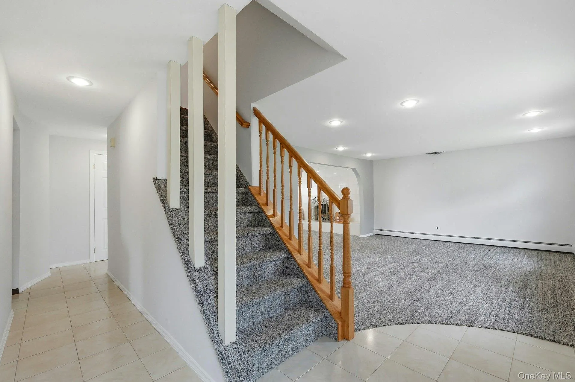 Split-level entryway featuring a carpeted staircase with a wood banister and white balusters Split-level entryway featuring a carpeted staircase with a wood banister and white balusters