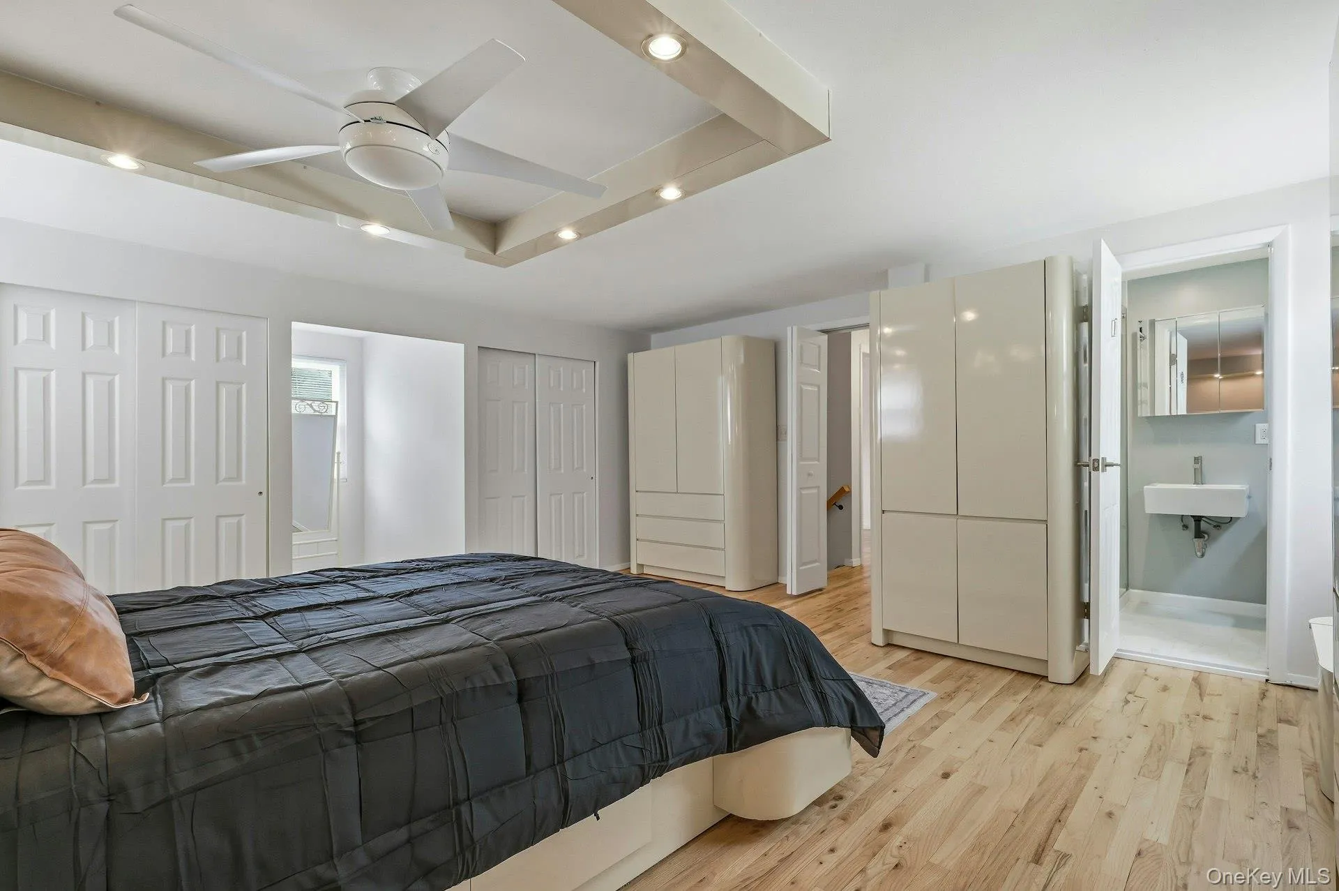 Recessed ceiling with integrated lighting, a ceiling fan, and wood-finish flooring Recessed ceiling with integrated lighting, a ceiling fan, and wood-finish flooring