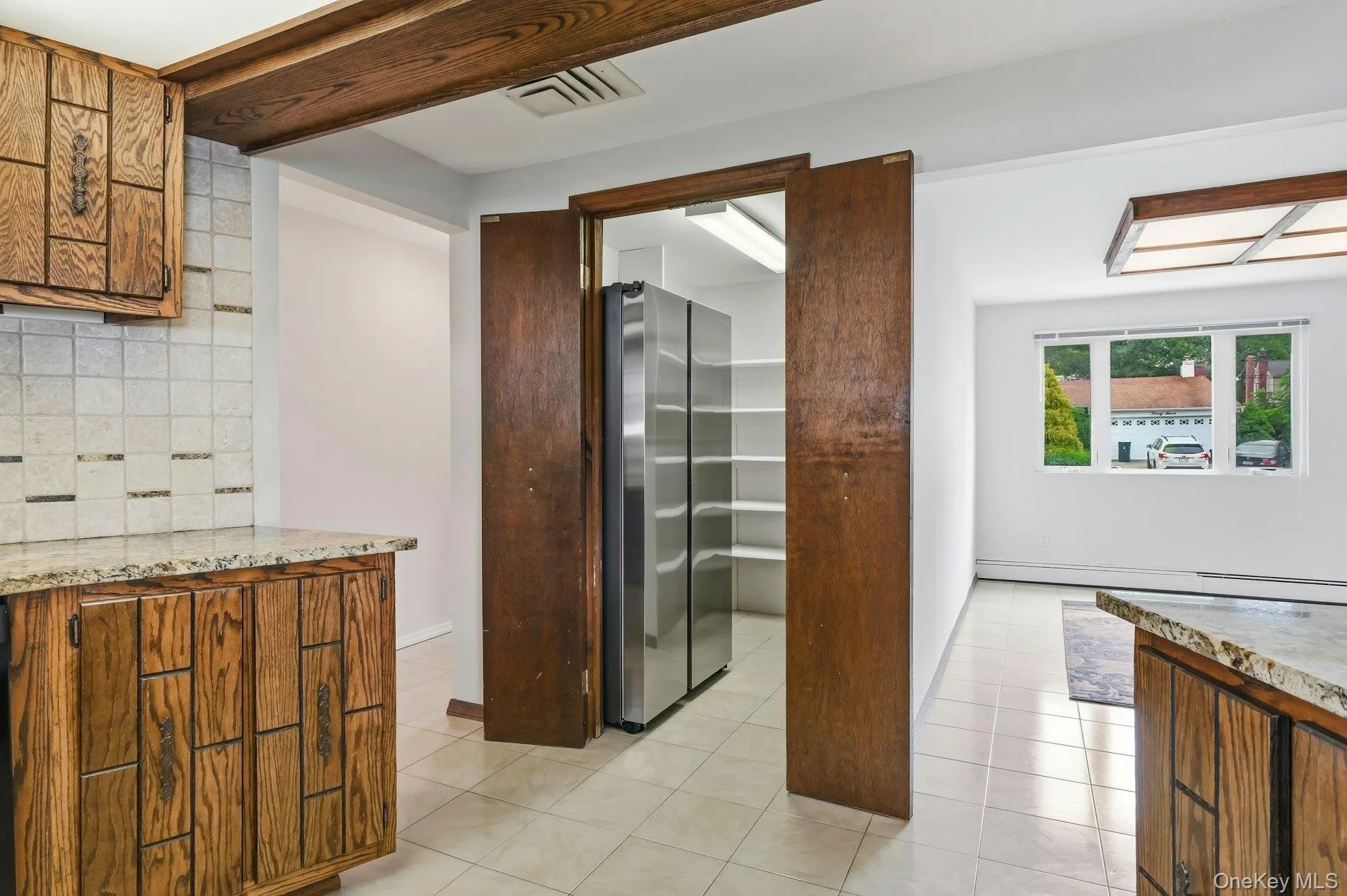 Kitchen with wood cabinetry, granite countertops, and tile backsplash Kitchen with wood cabinetry, granite countertops, and tile backsplash