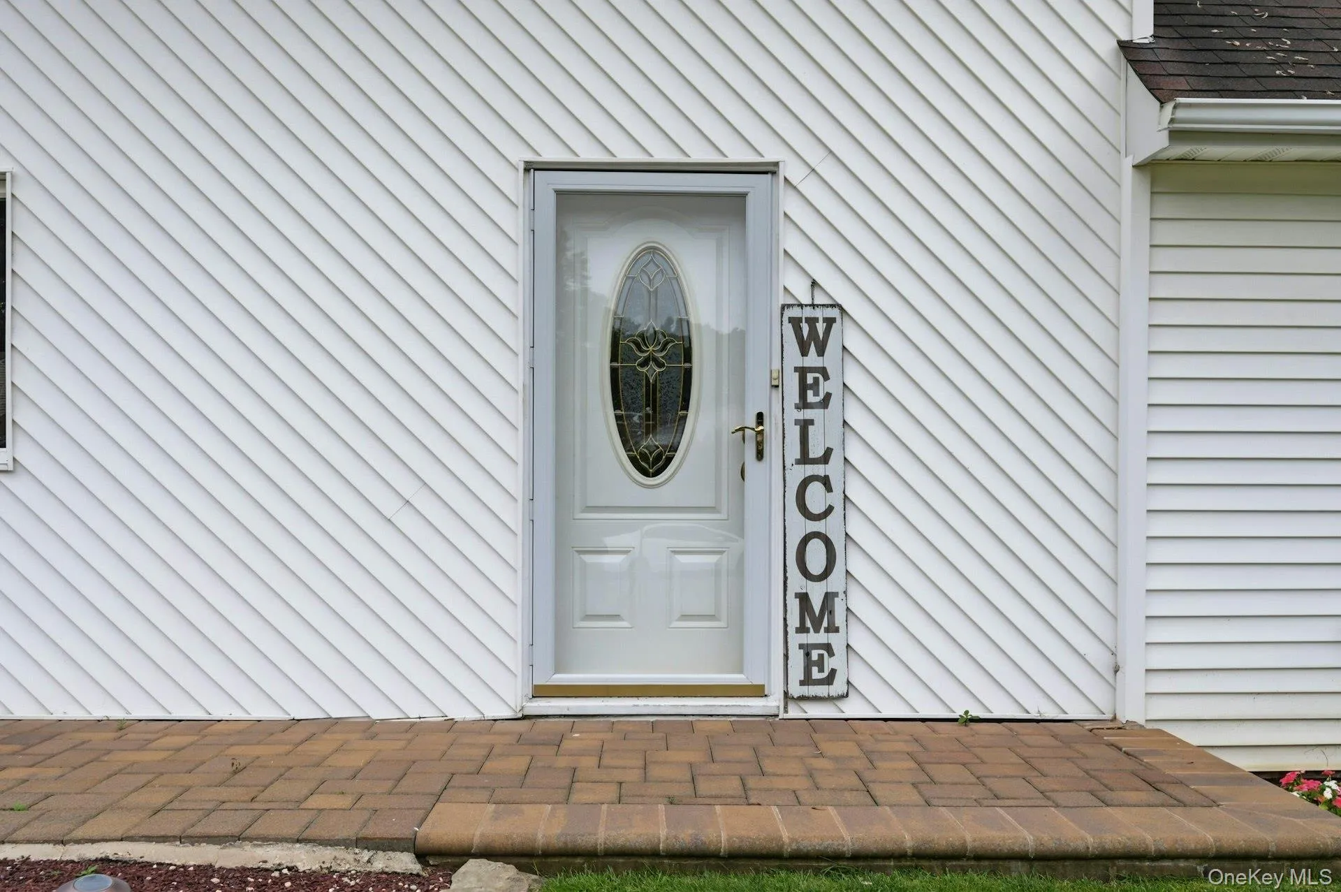 White exterior siding with diagonal paneling complemented by a brick paver walkway White exterior siding with diagonal paneling complemented by a brick paver walkway