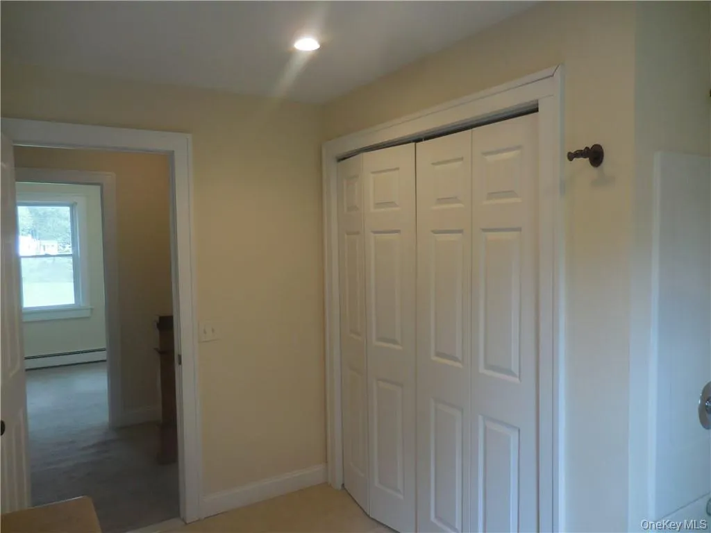 Unfurnished bedroom with a closet, a baseboard heating unit, and light carpet Unfurnished bedroom with a closet, a baseboard heating unit, and light carpet