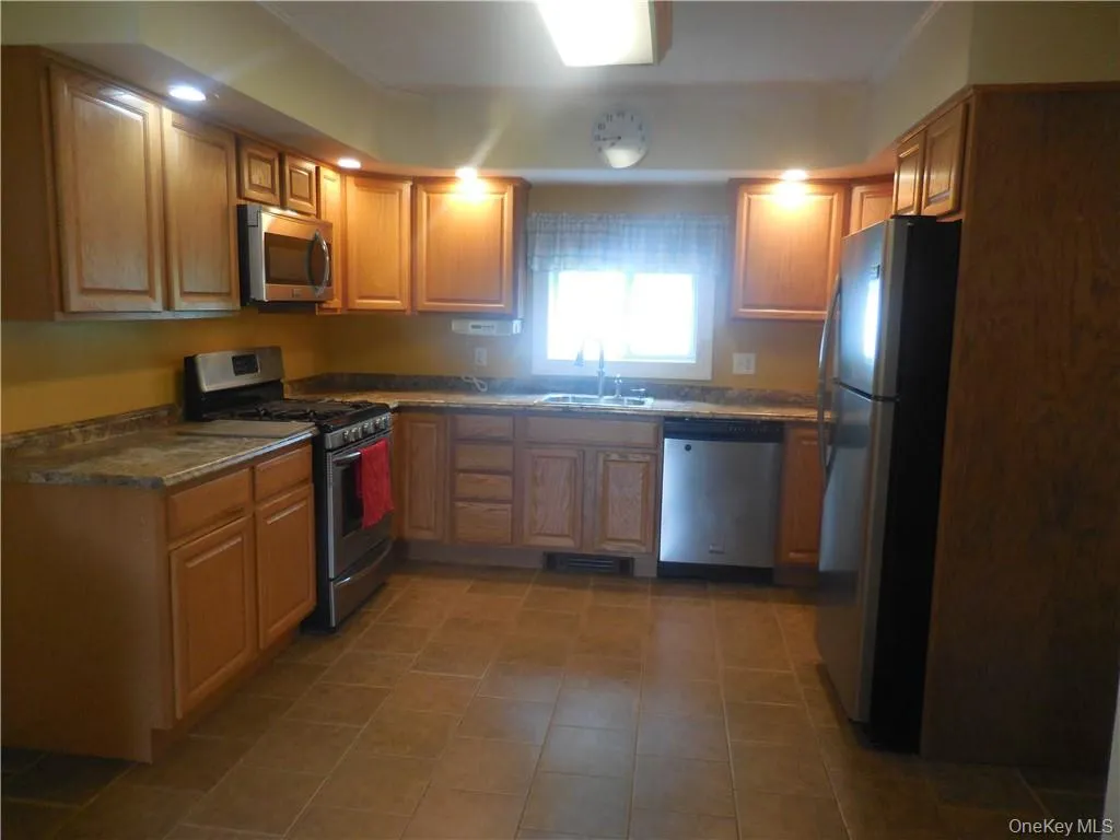 Kitchen with sink, stainless steel appliances, and tile patterned flooring Kitchen with sink, stainless steel appliances, and tile patterned flooring