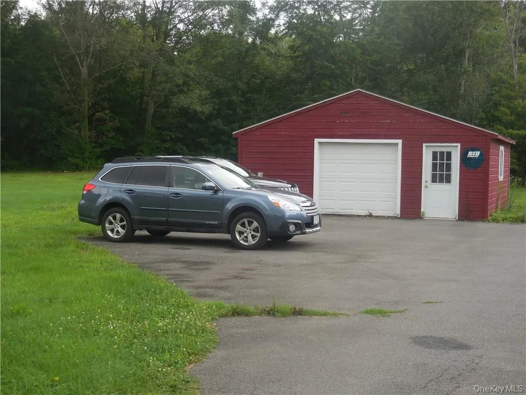 Small garage featuring a yard and extra parking area. Small garage featuring a yard and extra parking area.