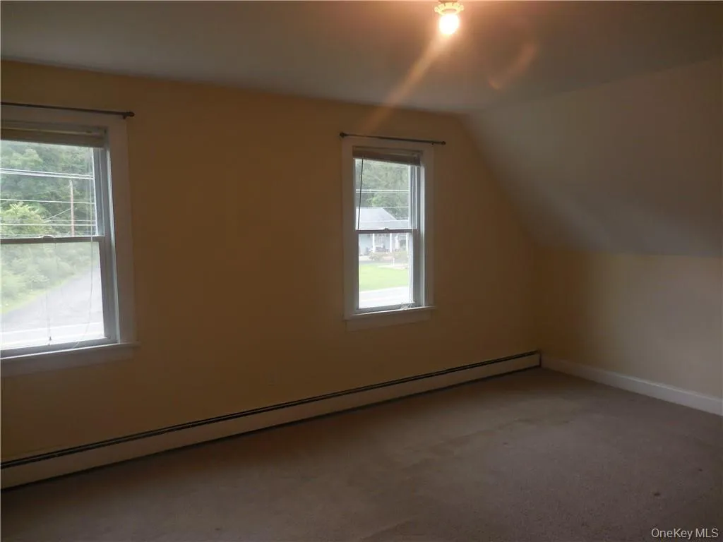 Bonus room with vaulted ceiling, baseboard heating, and carpet flooring Bonus room with vaulted ceiling, baseboard heating, and carpet flooring