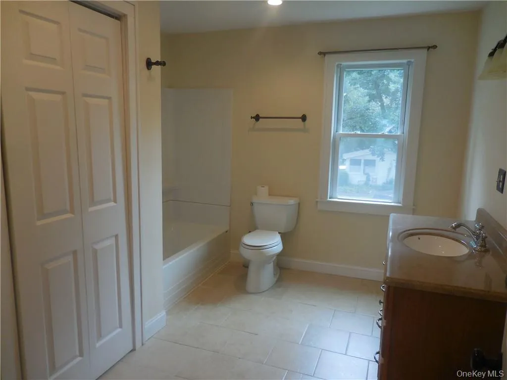 Full bathroom featuring bathing tub / shower combination, toilet, vanity, and tile patterned floors Full bathroom featuring bathing tub / shower combination, toilet, vanity, and tile patterned floors