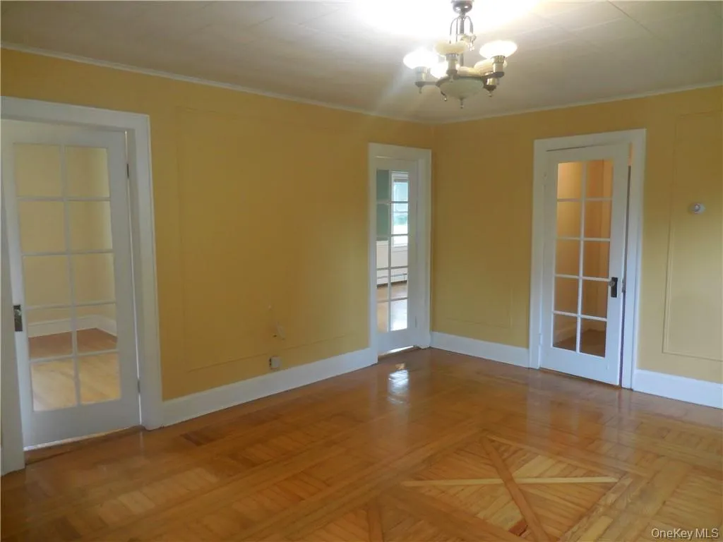 Spare room with a chandelier, french doors, and parquet flooring Spare room with a chandelier, french doors, and parquet flooring