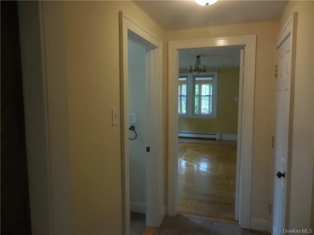 Corridor with tile patterned flooring, a baseboard radiator, and a chandelier Corridor with tile patterned flooring, a baseboard radiator, and a chandelier