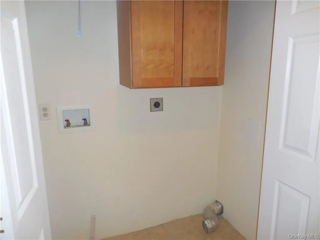 Laundry area with tile patterned floors, washer hookup, cabinets, and hookup for an electric dryer Laundry area with tile patterned floors, washer hookup, cabinets, and hookup for an electric dryer