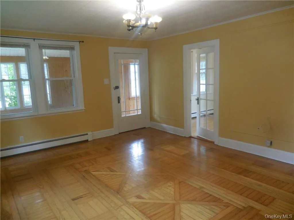 Entryway featuring light parquet flooring, a notable chandelier, and a baseboard heating unit Entryway featuring light parquet flooring, a notable chandelier, and a baseboard heating unit