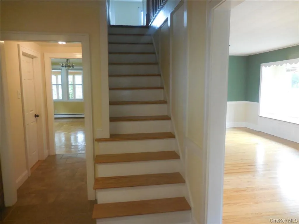 Stairs with a baseboard heating unit, hardwood / wood-style flooring, and a chandelier Stairs with a baseboard heating unit, hardwood / wood-style flooring, and a chandelier