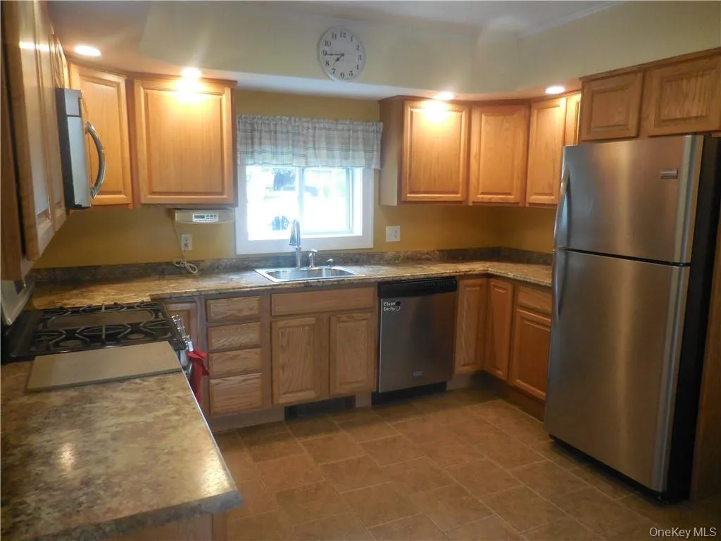 Kitchen with sink, stainless steel appliances, and dark tile patterned flooring Kitchen with sink, stainless steel appliances, and dark tile patterned flooring