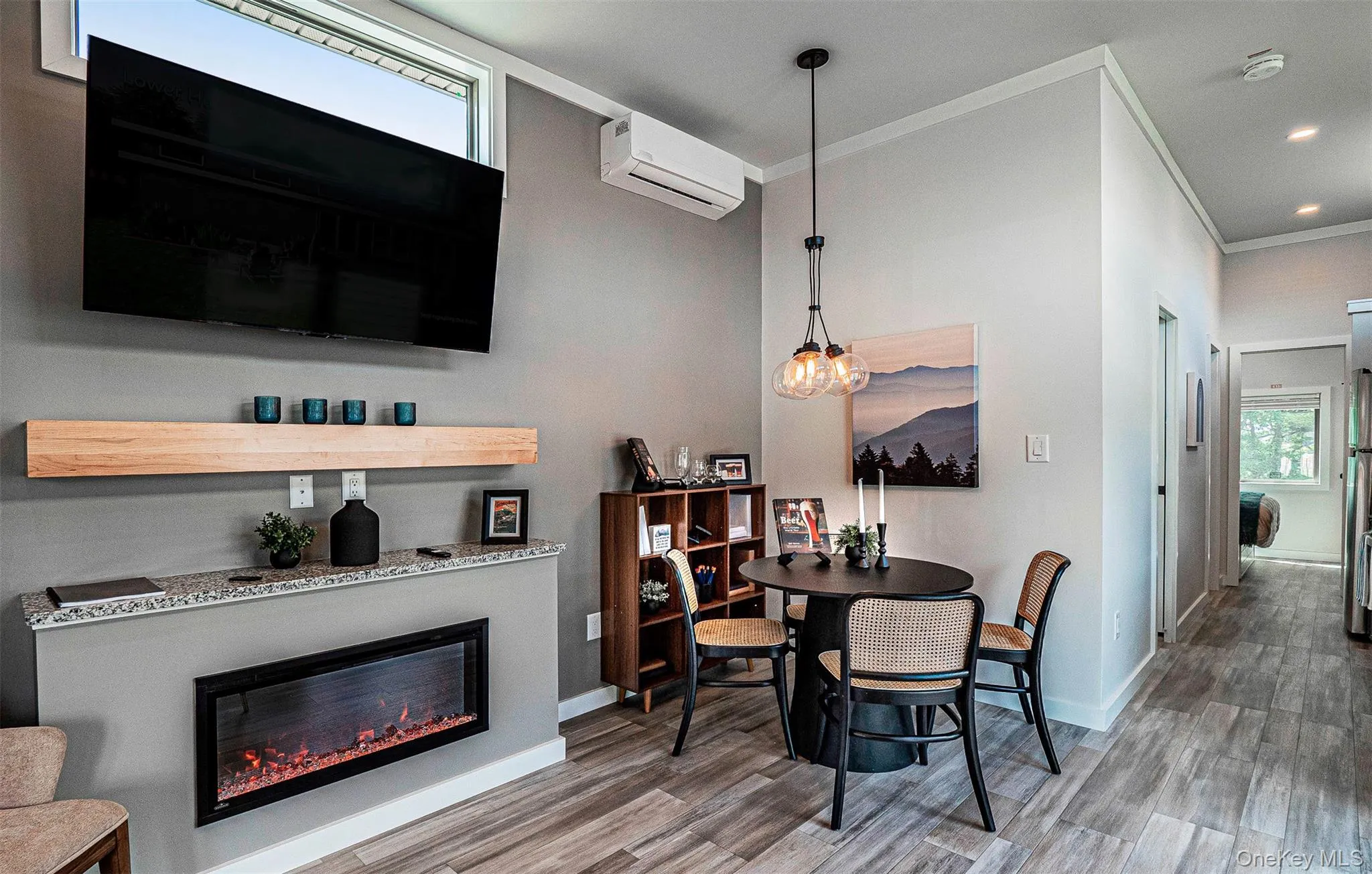 Dining room with a glass covered fireplace, light wood-style floors, ornamental molding, a wall unit AC, and recessed lighting Dining room with a glass covered fireplace, light wood-style floors, ornamental molding, a wall unit AC, and recessed lighting
