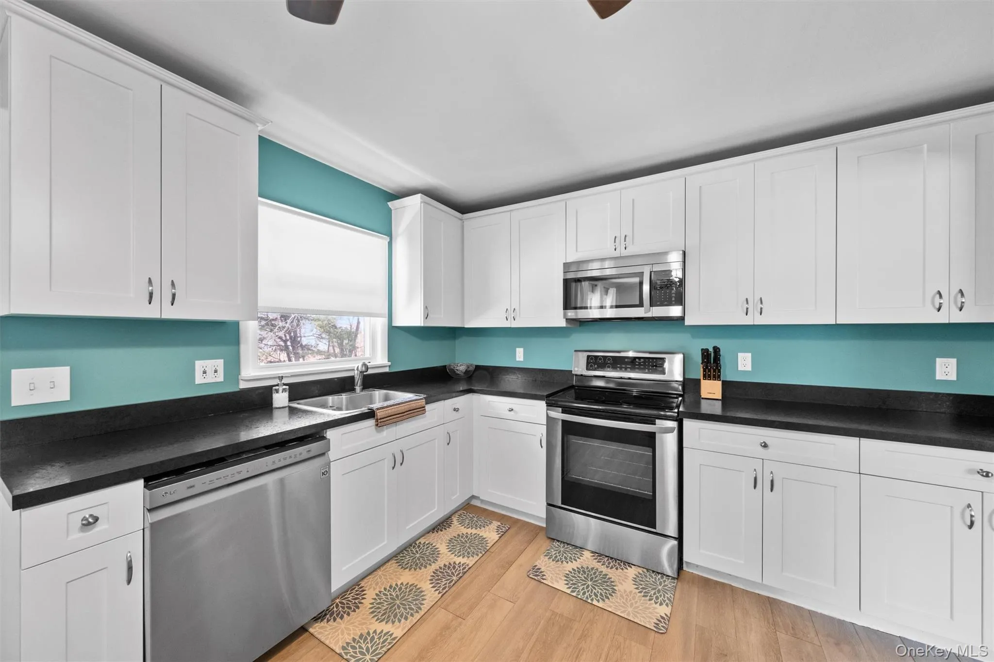 Kitchen featuring stainless steel appliances, dark countertops, and white cabinetry Kitchen featuring stainless steel appliances, dark countertops, and white cabinetry