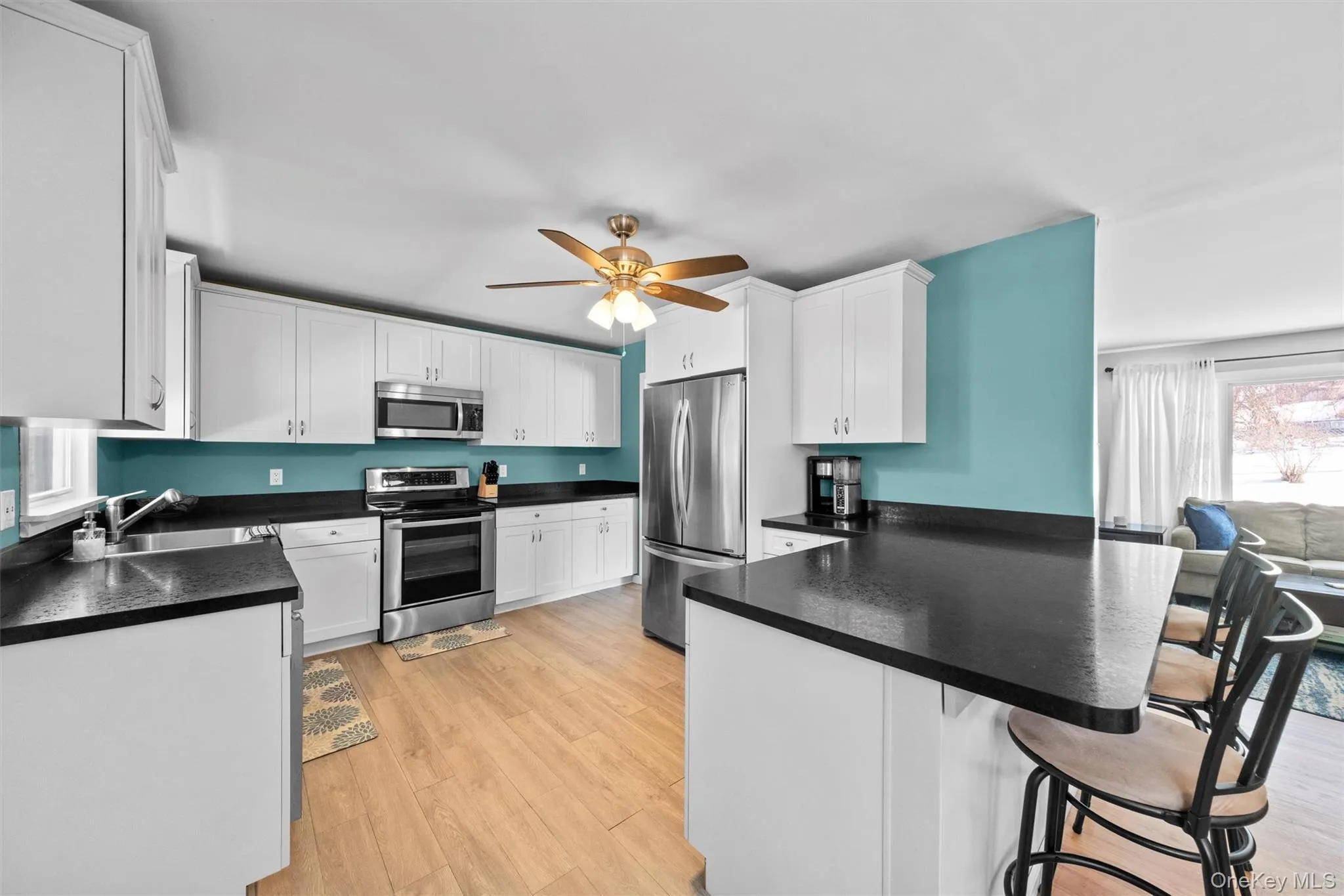 Kitchen with dark countertops, a peninsula, appliances with stainless steel finishes, and white cabinets Kitchen with dark countertops, a peninsula, appliances with stainless steel finishes, and white cabinets