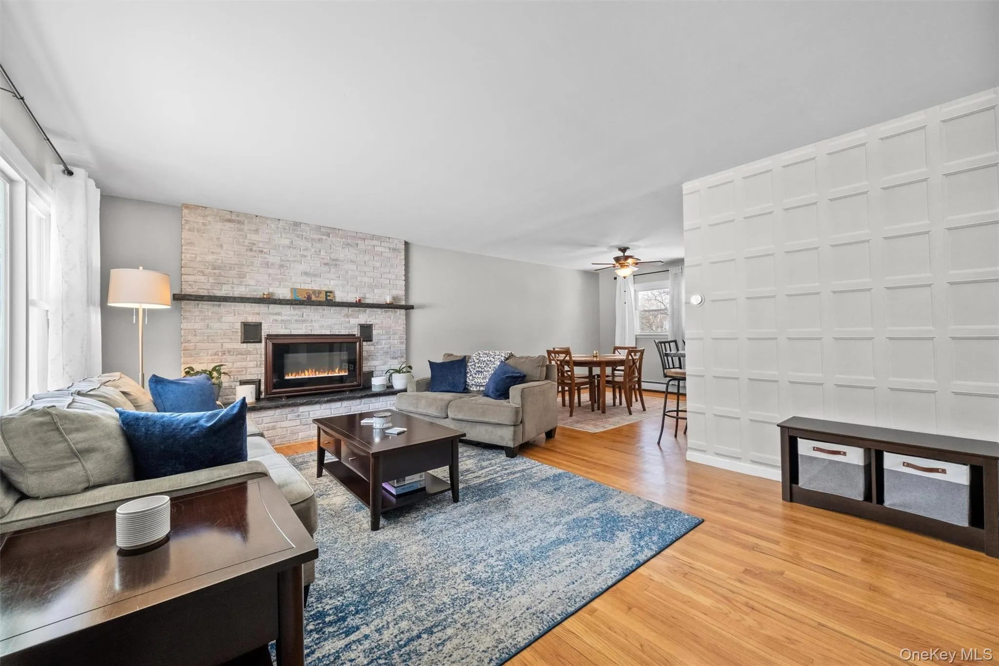 Living room with a fireplace, wood finished floors, and a ceiling fan Living room with a fireplace, wood finished floors, and a ceiling fan