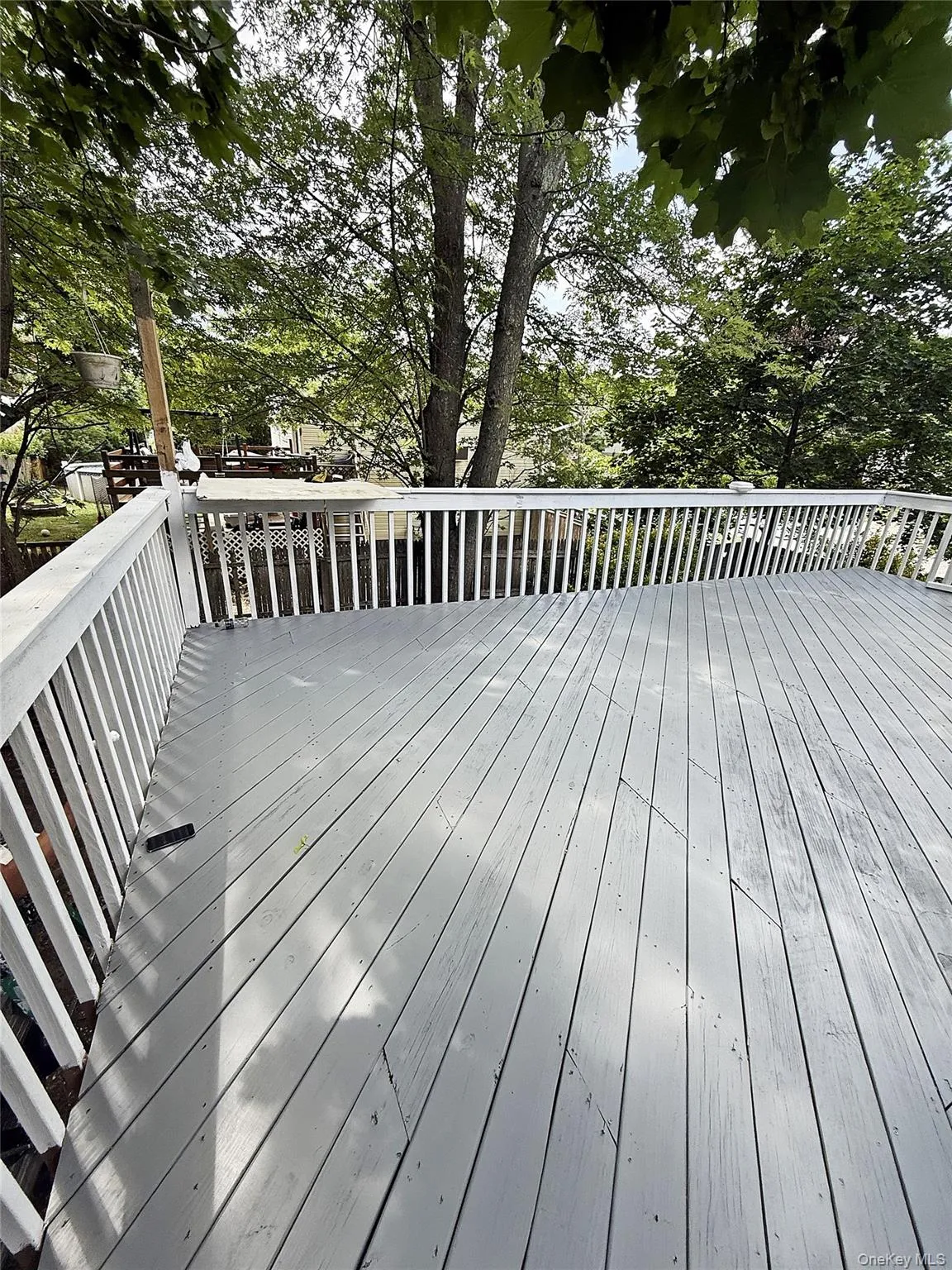 Expansive outdoor deck featuring painted wood planks and a white railing Expansive outdoor deck featuring painted wood planks and a white railing