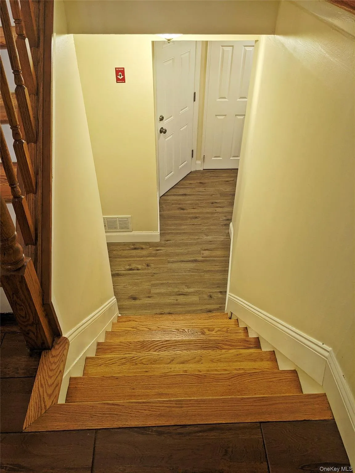 Hardwood staircase with natural wood treads and a dark wood newel post leading to a lower level with wood-finish flooring Hardwood staircase with natural wood treads and a dark wood newel post leading to a lower level with wood-finish flooring