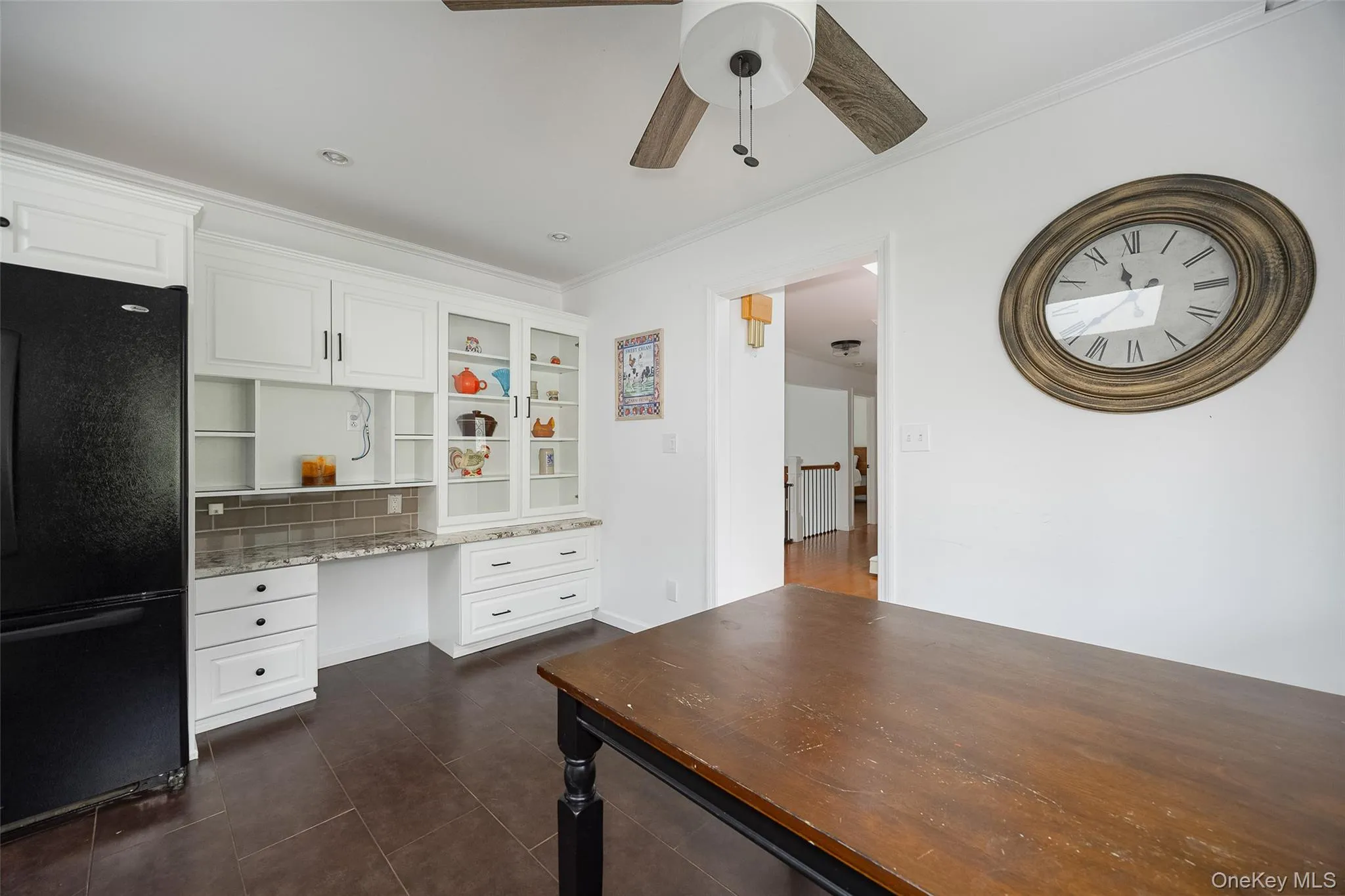 Built-in white cabinetry with glass-front display uppers, granite-look countertops, and a tiled backsplash Built-in white cabinetry with glass-front display uppers, granite-look countertops, and a tiled backsplash