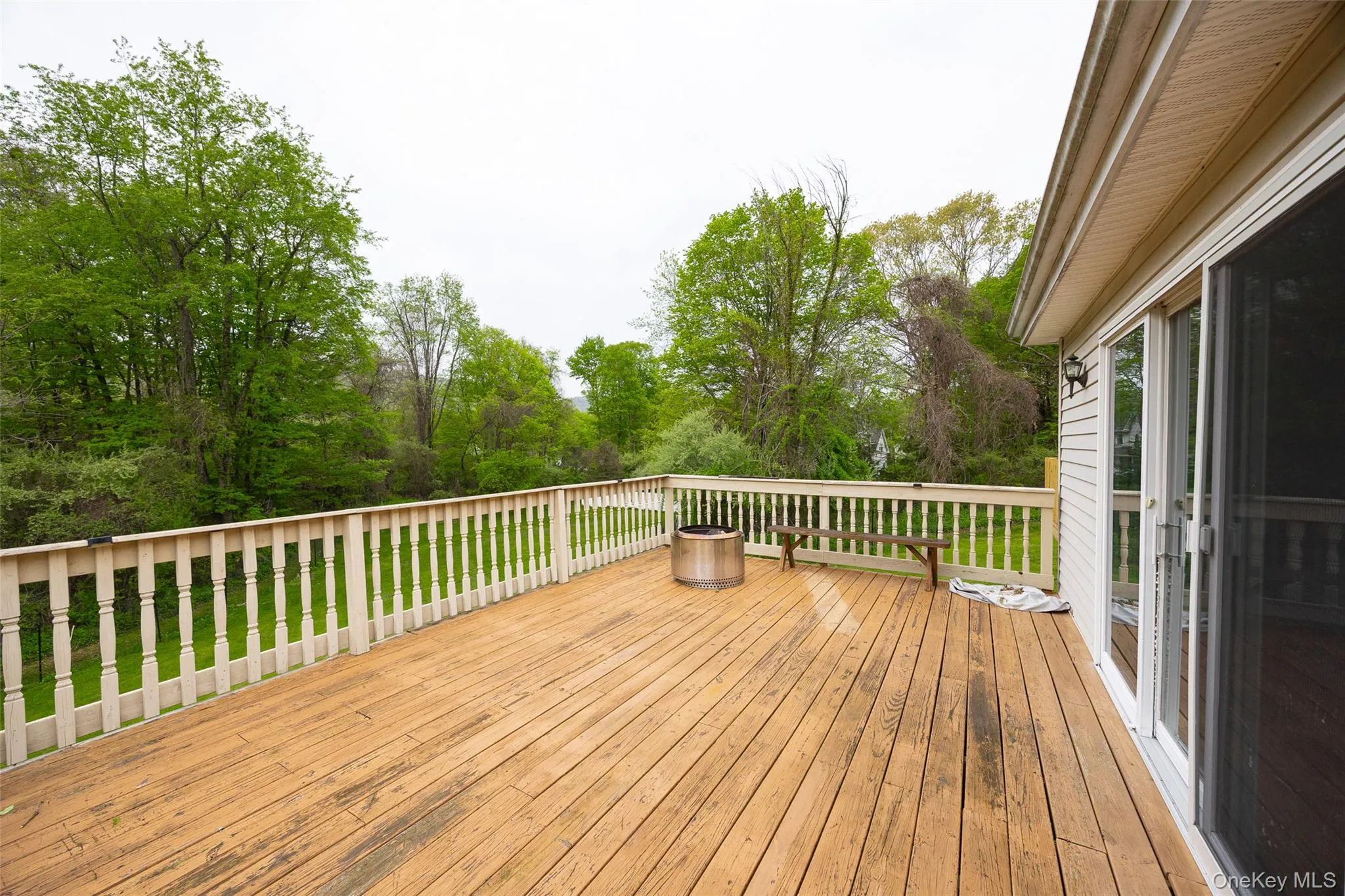 Expansive wood deck featuring a white spindle railing and direct access to interior spaces via sliding glass doors Expansive wood deck featuring a white spindle railing and direct access to interior spaces via sliding glass doors