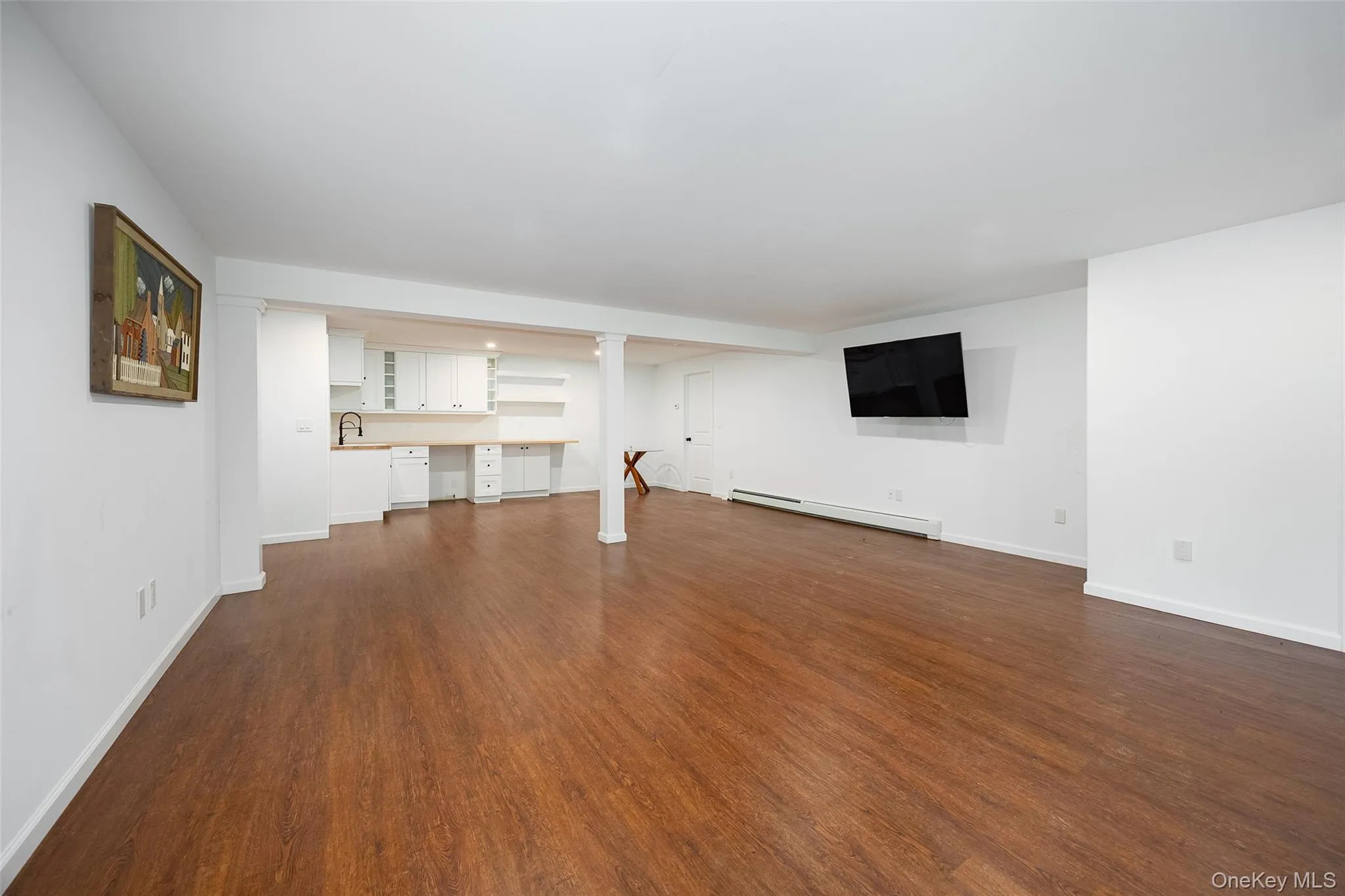 Spacious finished room featuring warm wood-finish flooring, crisp white walls, and recessed lighting Spacious finished room featuring warm wood-finish flooring, crisp white walls, and recessed lighting