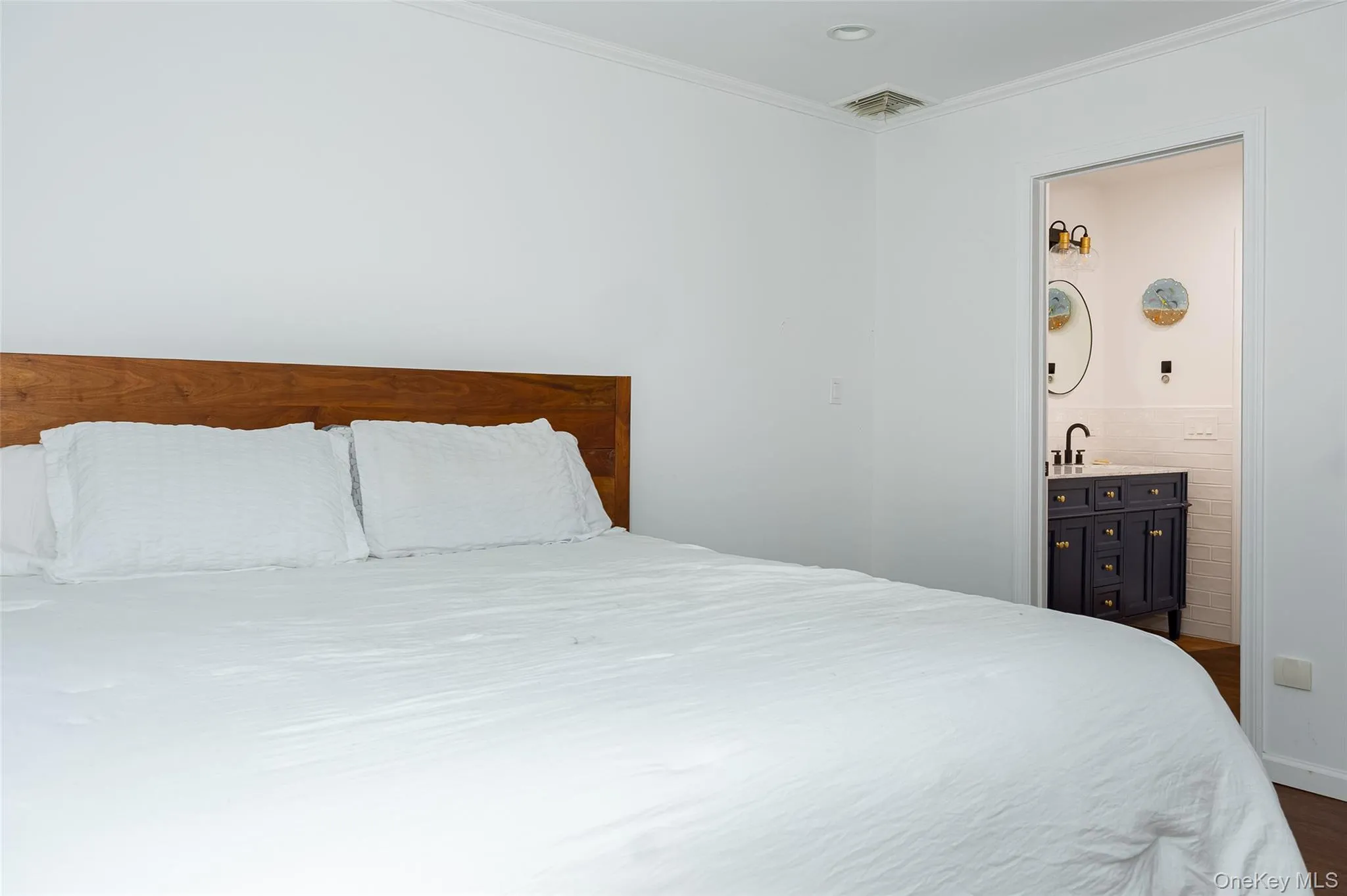 Spacious bedroom with white walls and a warm wood-finish headboard Spacious bedroom with white walls and a warm wood-finish headboard