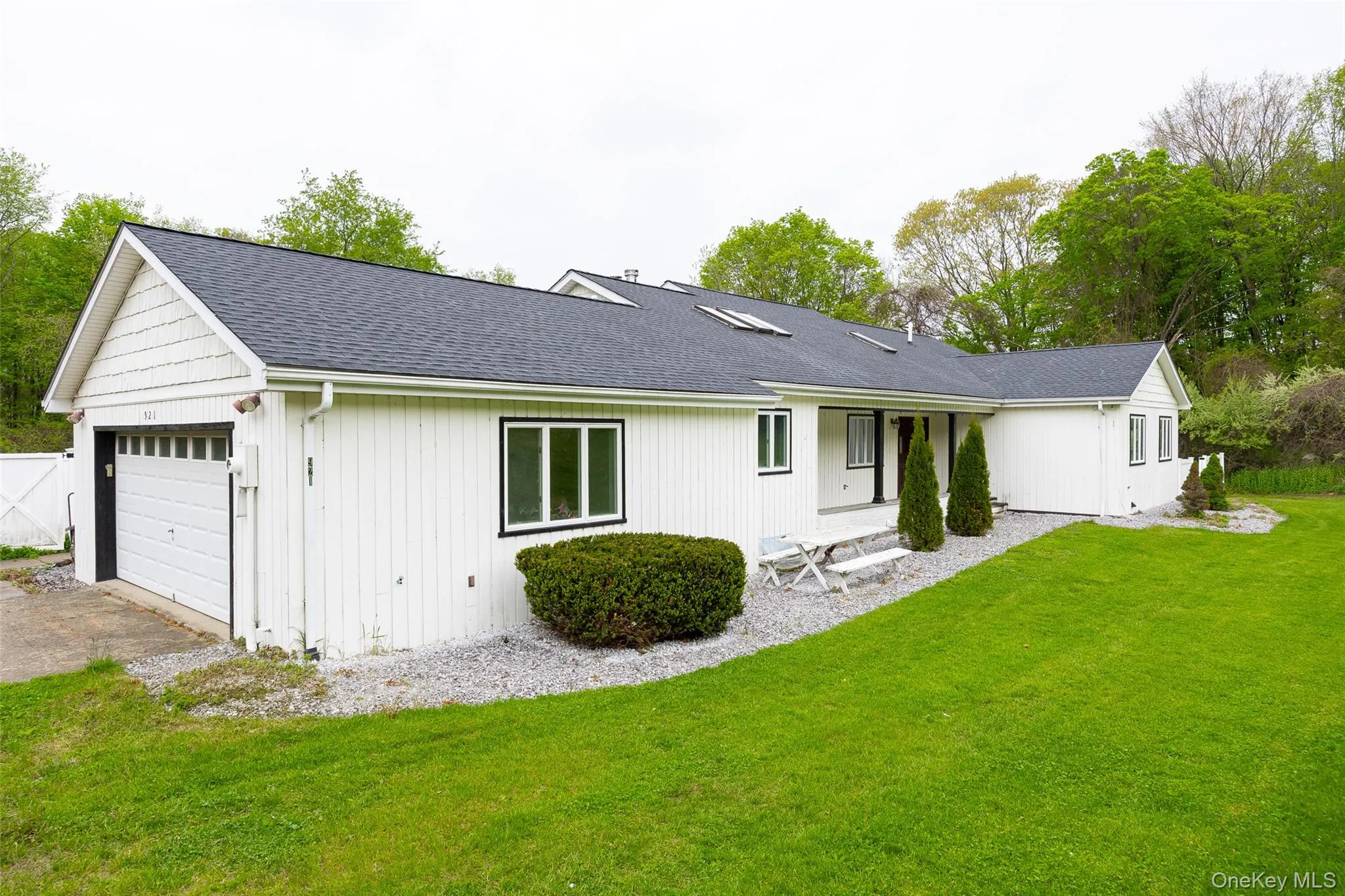 Single-story residence featuring white vertical siding and a dark shingle roof Single-story residence featuring white vertical siding and a dark shingle roof