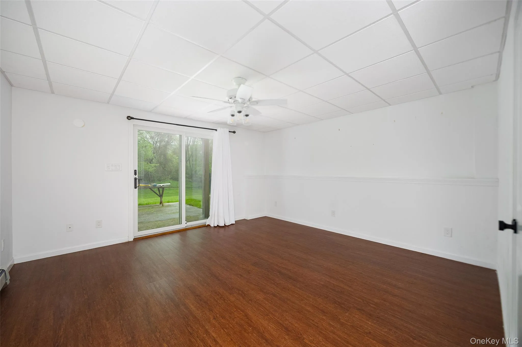 Spacious room with wood-finish flooring, white walls, and a drop ceiling Spacious room with wood-finish flooring, white walls, and a drop ceiling