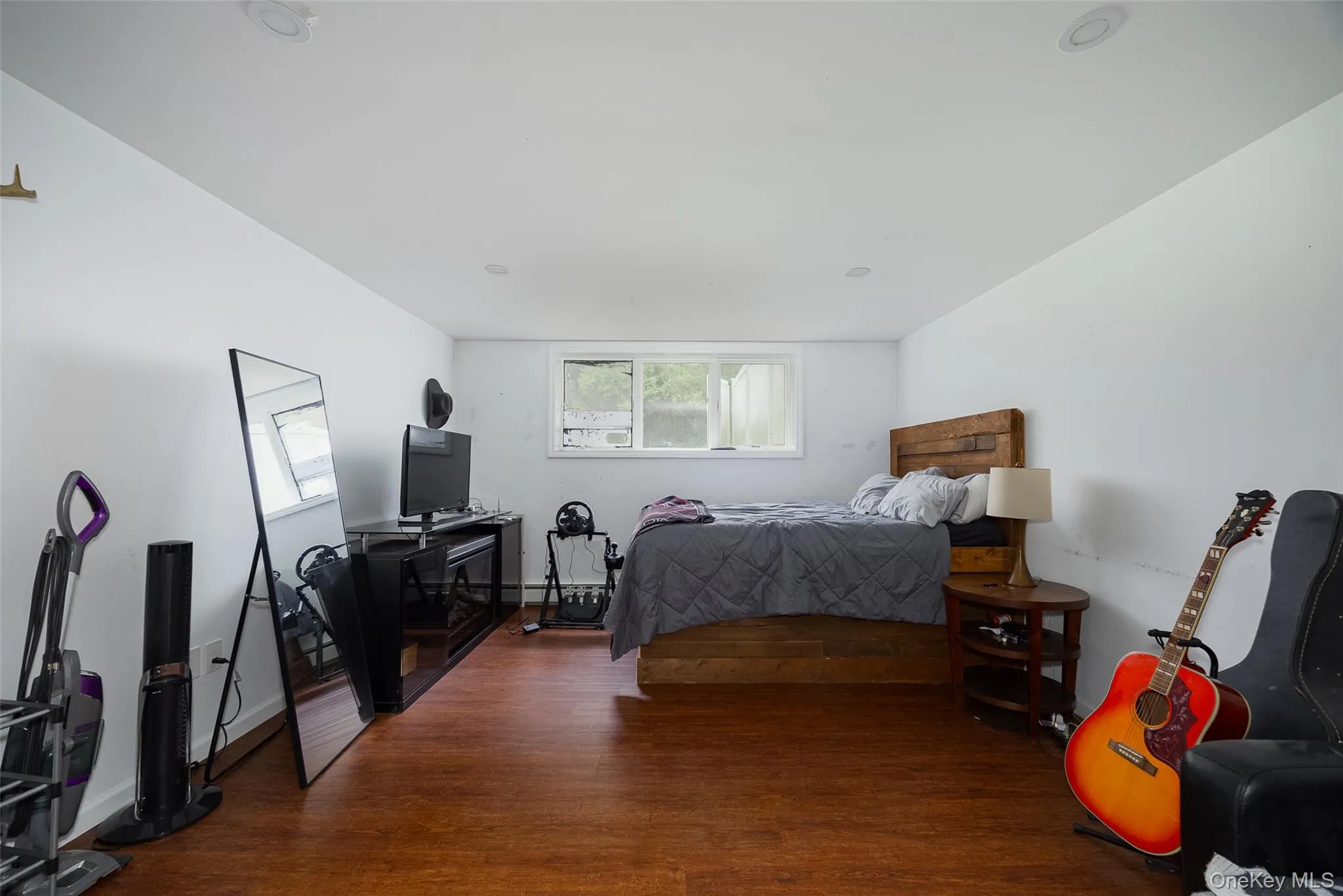Spacious room featuring wood-finish flooring, white painted walls, and recessed lighting Spacious room featuring wood-finish flooring, white painted walls, and recessed lighting