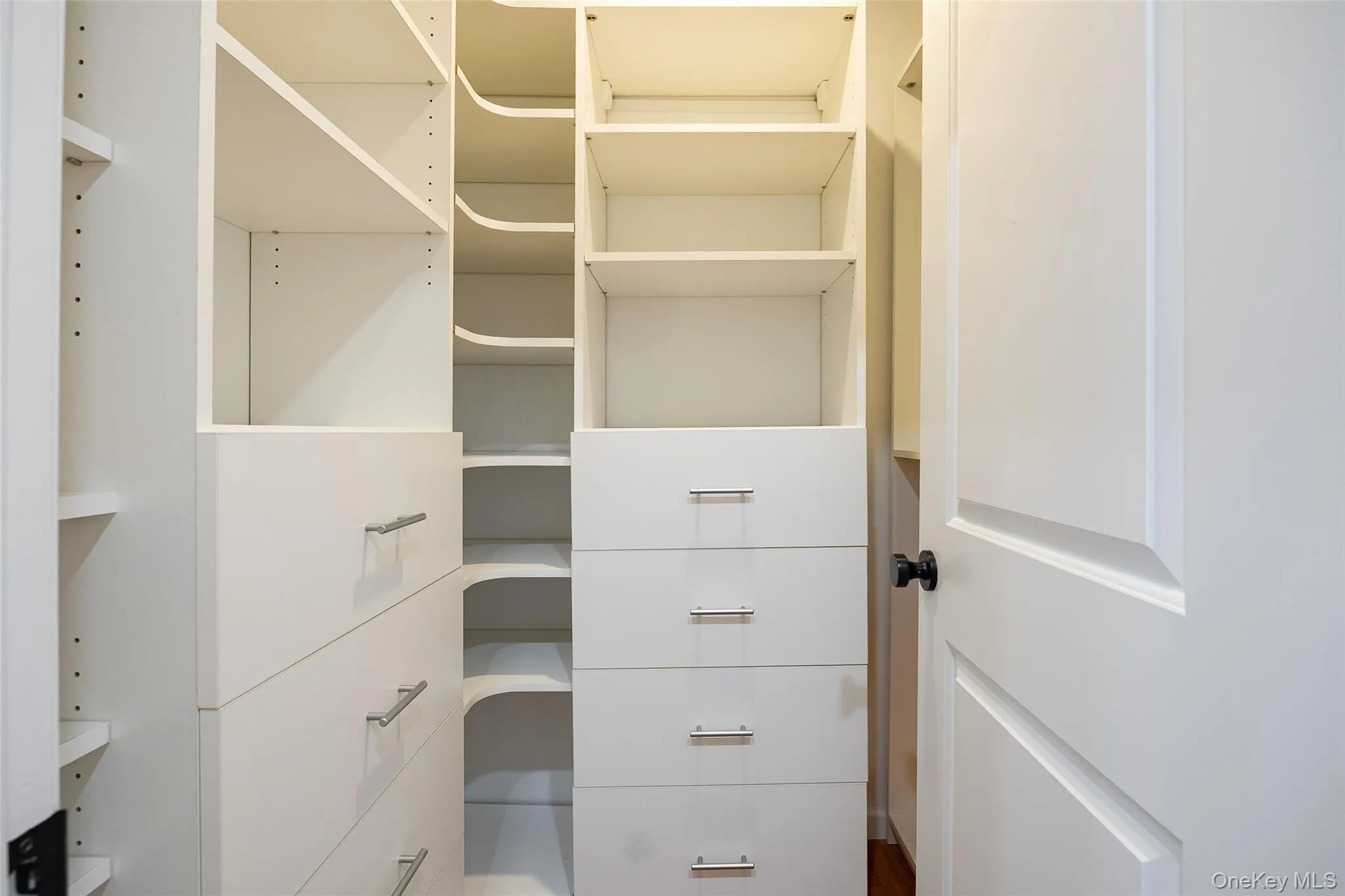 Custom closet system featuring multiple shelving units, built-in drawers with modern pulls, and integrated corner shelving Custom closet system featuring multiple shelving units, built-in drawers with modern pulls, and integrated corner shelving