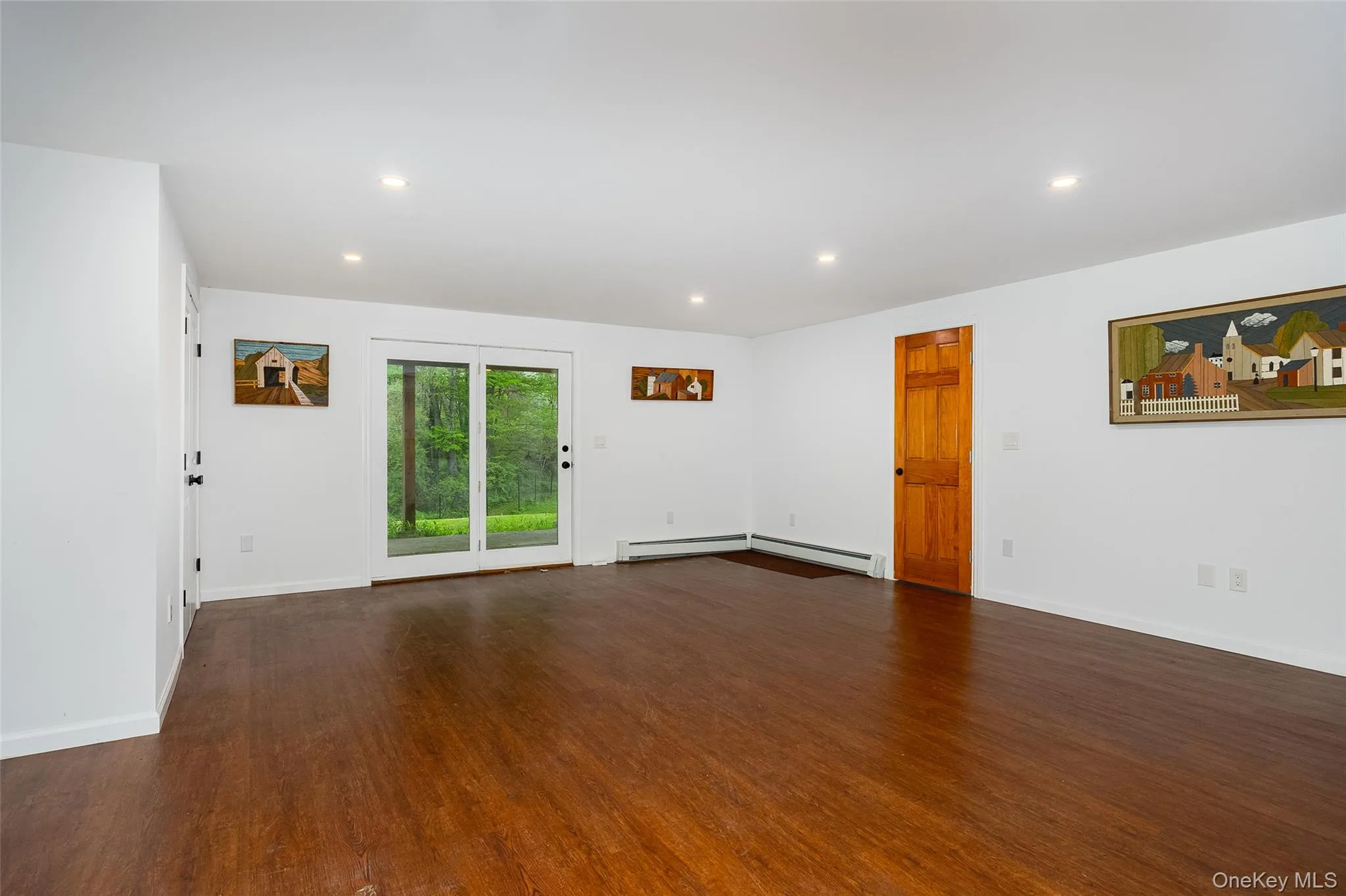 Spacious room featuring wood-finish flooring, recessed lighting, and white baseboards Spacious room featuring wood-finish flooring, recessed lighting, and white baseboards
