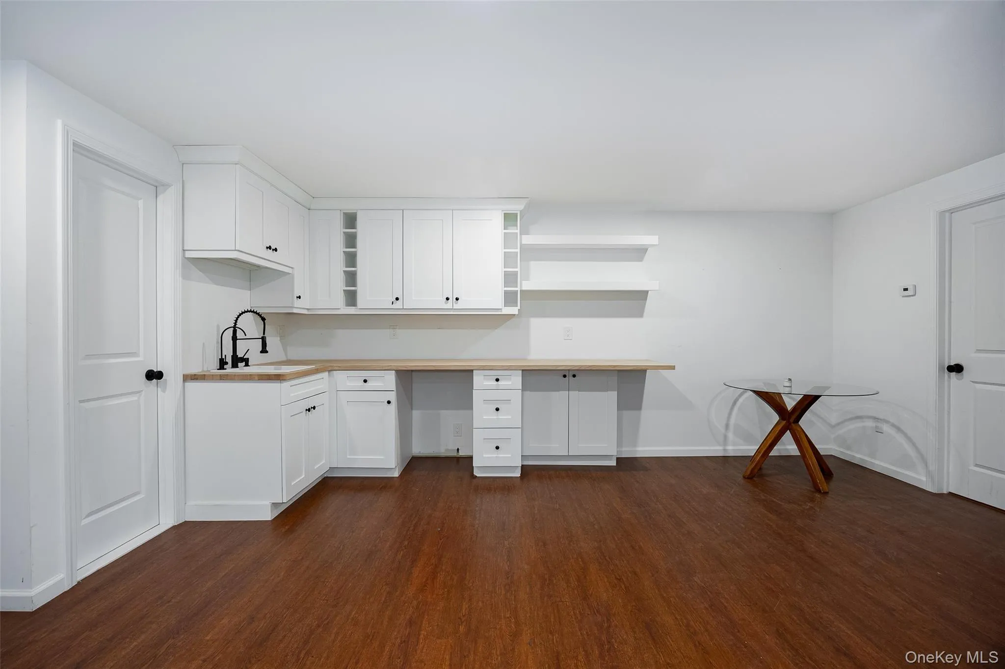White cabinetry with a wood-finish countertop, undermount sink, and matte black faucet White cabinetry with a wood-finish countertop, undermount sink, and matte black faucet
