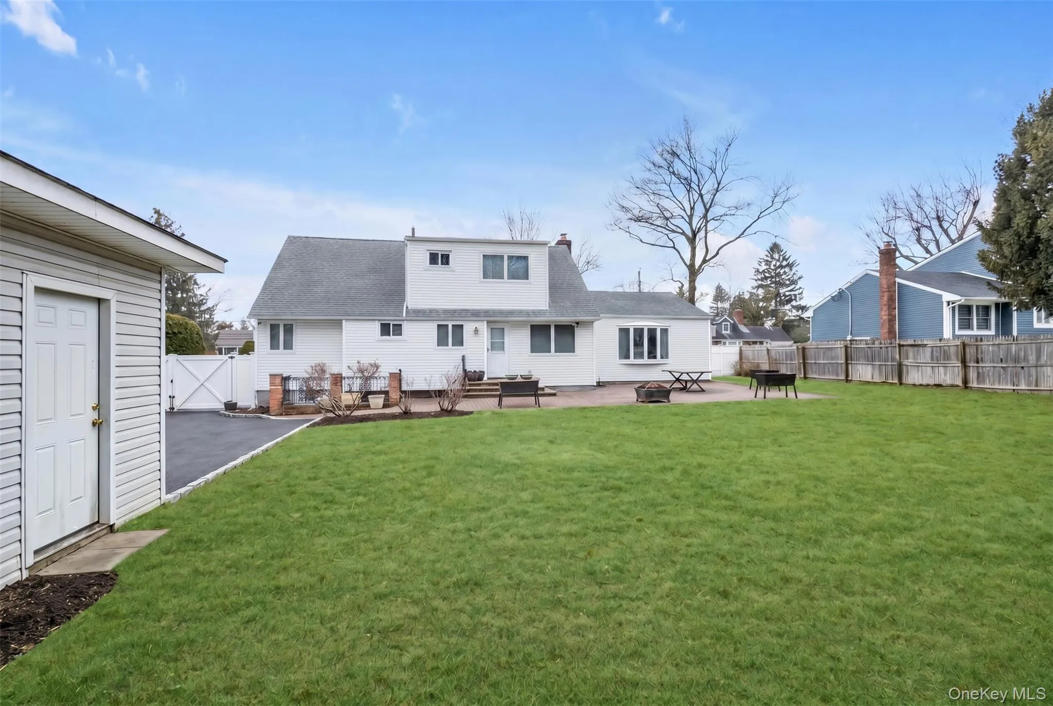 Spacious green lawn with a white detached shed and paved driveway Spacious green lawn with a white detached shed and paved driveway