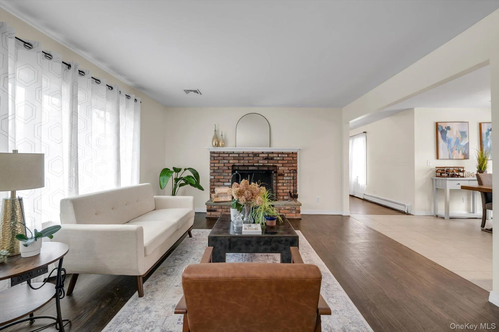 Living area featuring a brick fireplace with a stone hearth, dark wood-finish flooring, and light-toned walls Living area featuring a brick fireplace with a stone hearth, dark wood-finish flooring, and light-toned walls