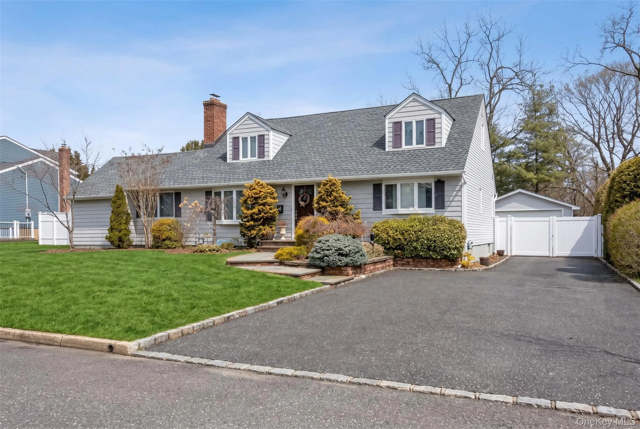 Light gray siding exterior with a dark shingle roof and brick chimney Light gray siding exterior with a dark shingle roof and brick chimney