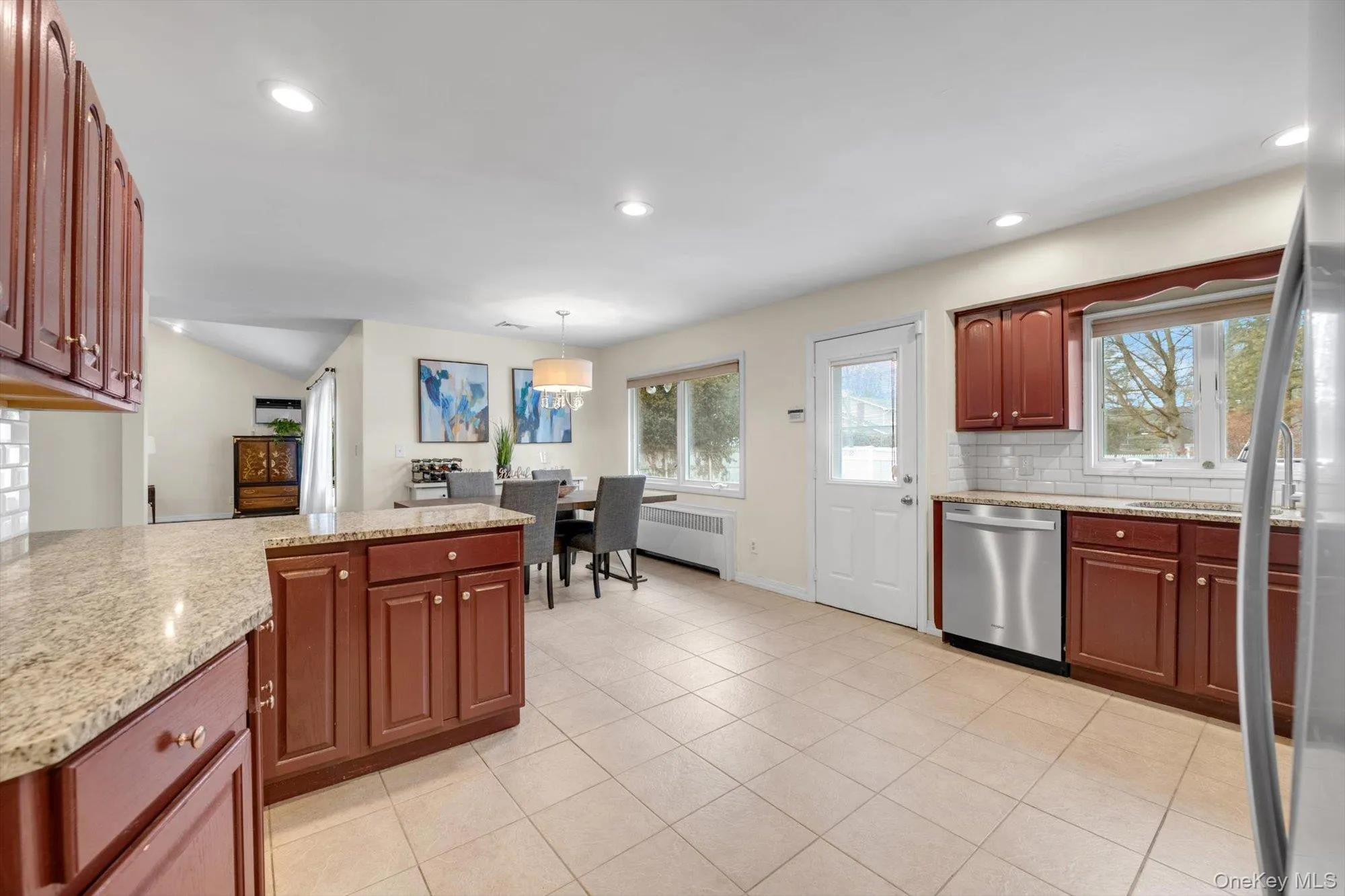 Open-concept kitchen and dining area featuring tile flooring, recessed lighting, and rich wood cabinetry Open-concept kitchen and dining area featuring tile flooring, recessed lighting, and rich wood cabinetry