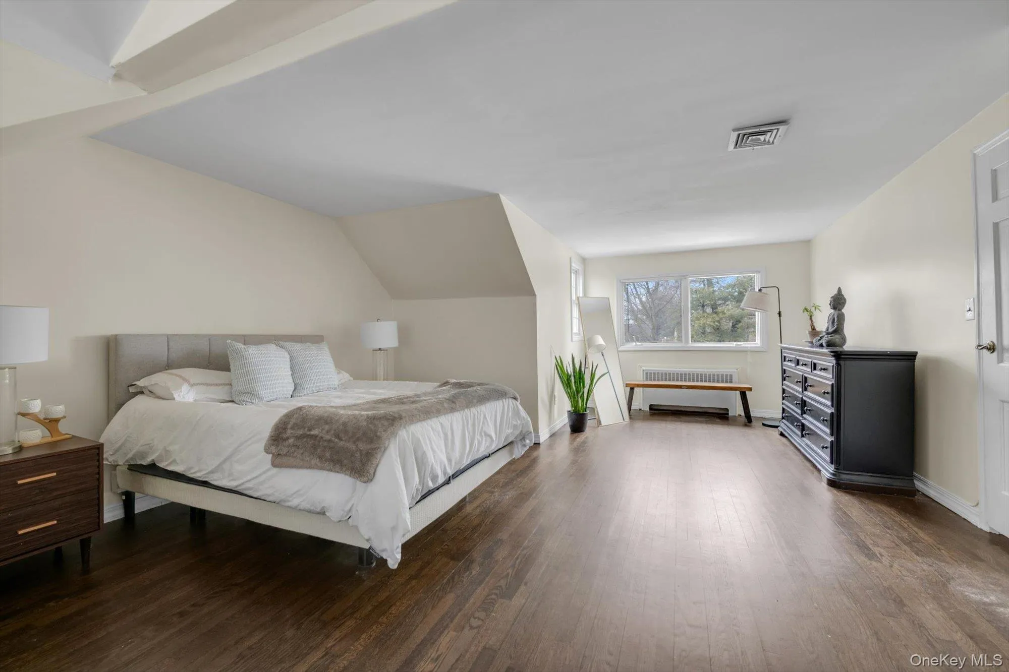 Spacious room featuring rich wood-finish flooring, ample natural light from multiple windows, and a neutral color palette Spacious room featuring rich wood-finish flooring, ample natural light from multiple windows, and a neutral color palette