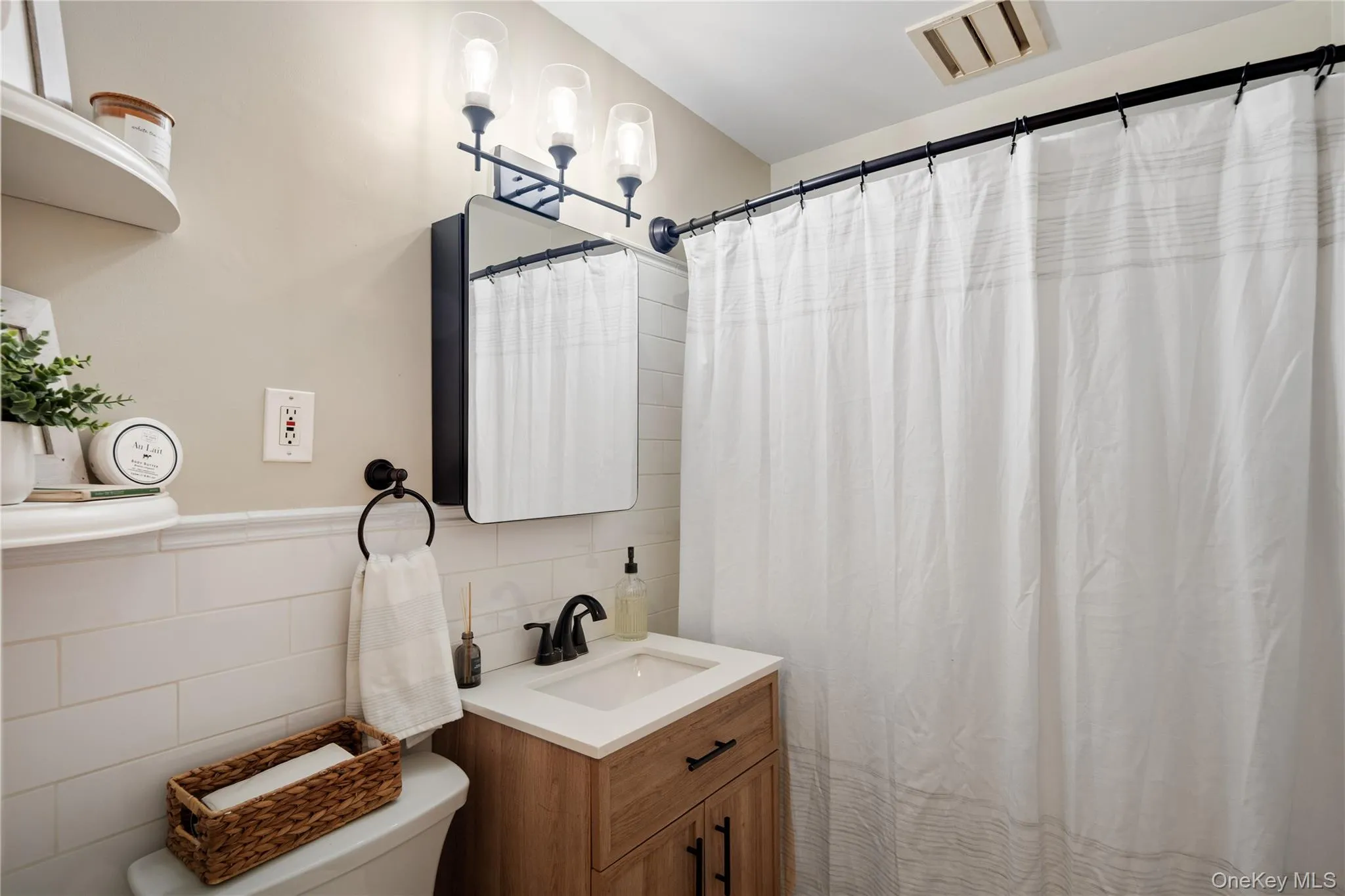 The tastefully updated hall bath features a quartz-top wood vanity, subway tile walls, a tub-shower combo, and built-in shelves. The tastefully updated hall bath features a quartz-top wood vanity, subway tile walls, a tub-shower combo, and built-in shelves.