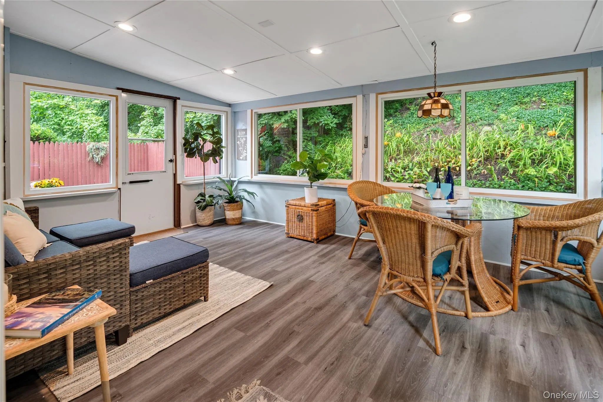 The three-season room, with walls of windows offering lush landscaped views and a door leading to the wraparound deck, extends the main living space and is the perfect spot to relax and entertain. The three-season room, with walls of windows offering lush landscaped views and a door leading to the wraparound deck, extends the main living space and is the perfect spot to relax and entertain.