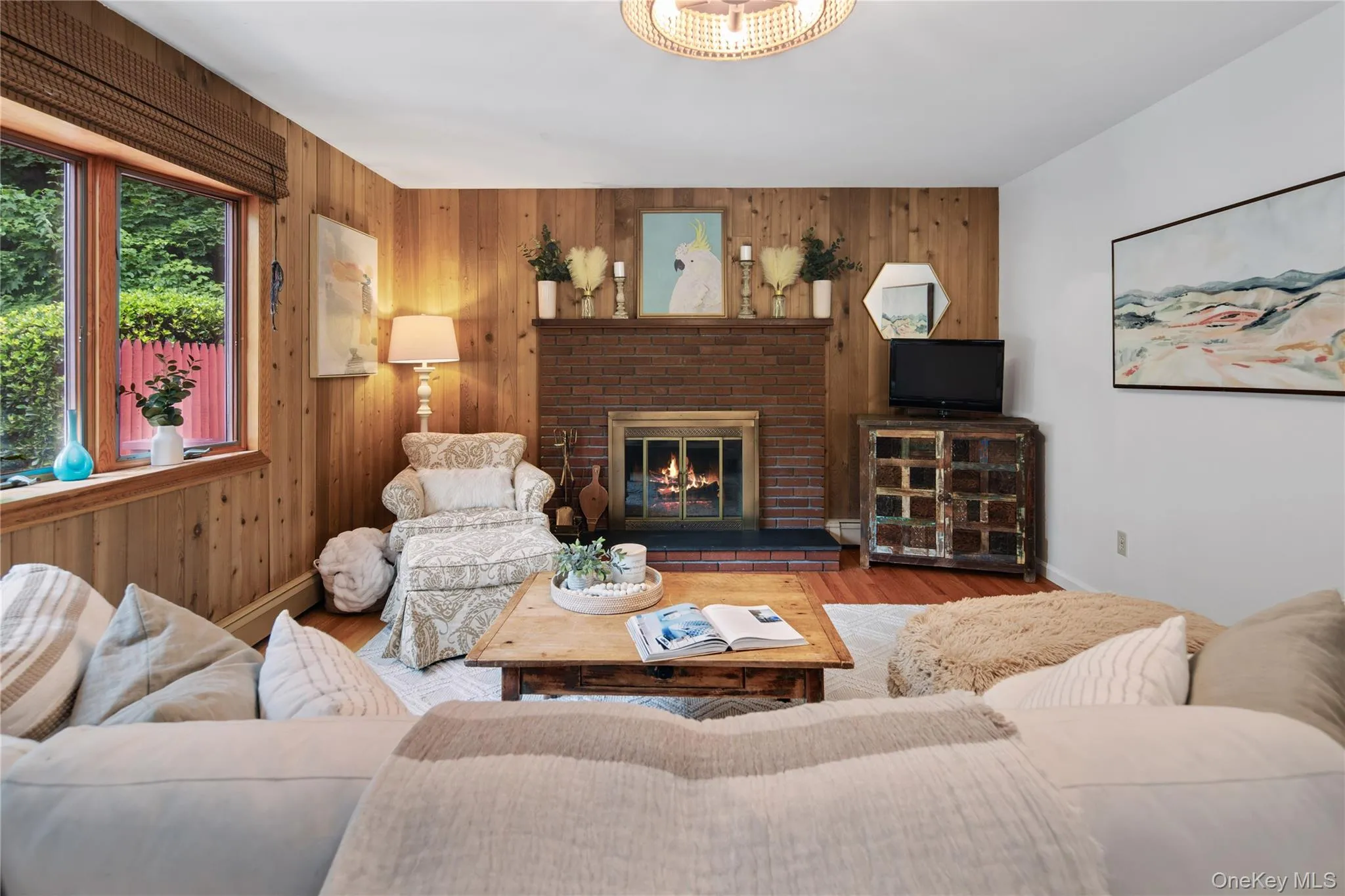 The warm and cozy living room is anchored by a wood-burning fireplace and a bay window, highlighted by wood accent walls. The warm and cozy living room is anchored by a wood-burning fireplace and a bay window, highlighted by wood accent walls.