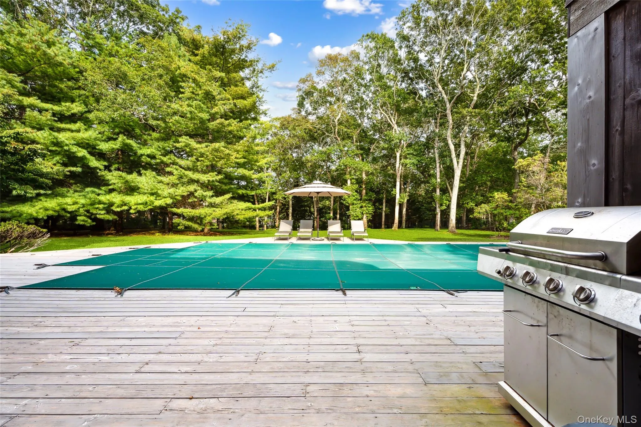 View of pool featuring a covered pool, a gazebo, view of scattered trees, and a wooden deck View of pool featuring a covered pool, a gazebo, view of scattered trees, and a wooden deck