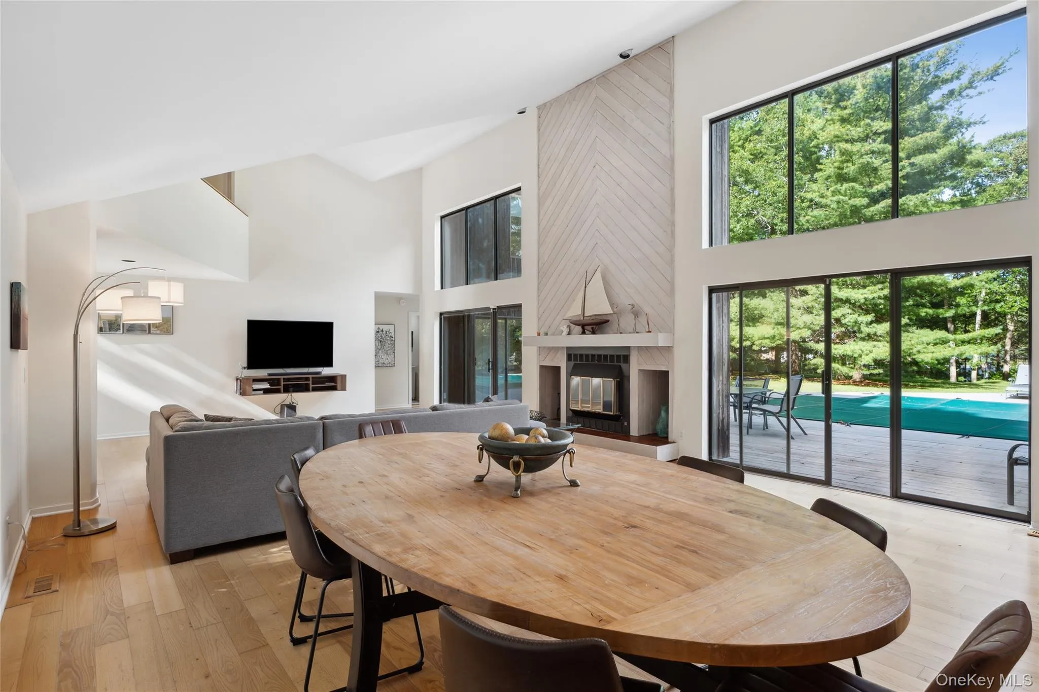 Dining space featuring a tiled fireplace, light wood-style floors, and a high ceiling Dining space featuring a tiled fireplace, light wood-style floors, and a high ceiling