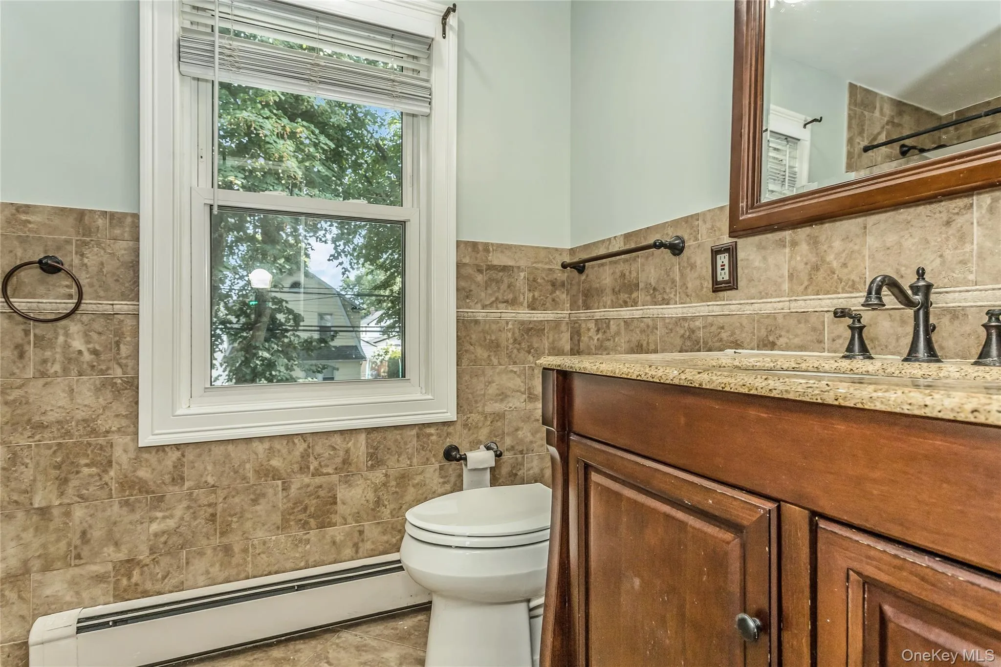 Bathroom with tile walls, a baseboard heating unit, vanity, healthy amount of natural light, and a wainscoted wall Bathroom with tile walls, a baseboard heating unit, vanity, healthy amount of natural light, and a wainscoted wall