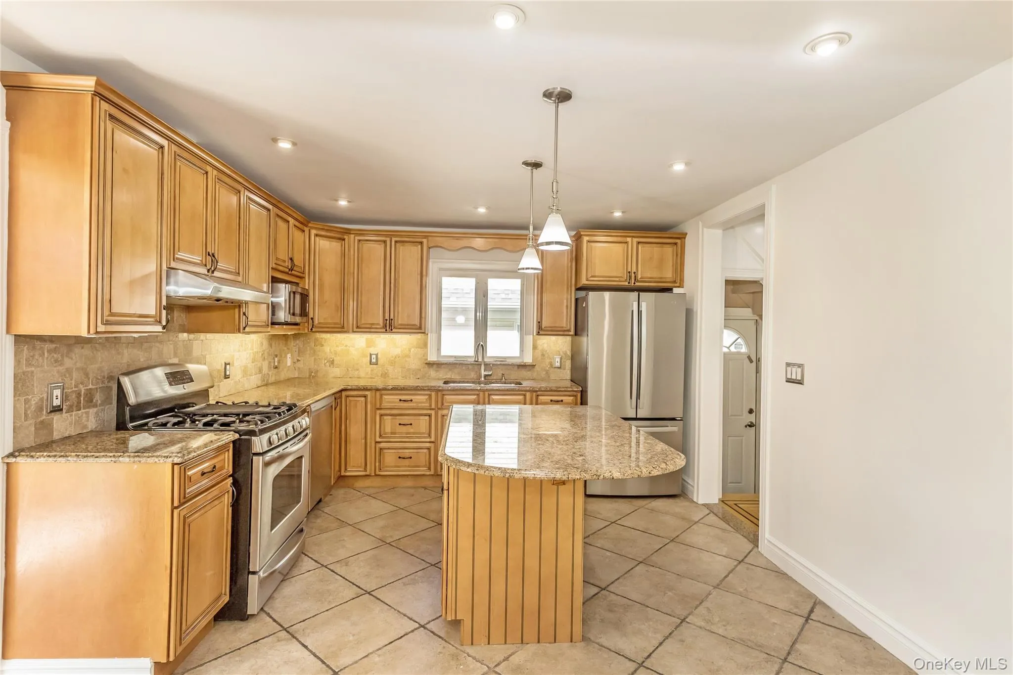 Kitchen featuring stainless steel appliances, light stone countertops, tasteful backsplash, hanging light fixtures, and light tile patterned floors Kitchen featuring stainless steel appliances, light stone countertops, tasteful backsplash, hanging light fixtures, and light tile patterned floors